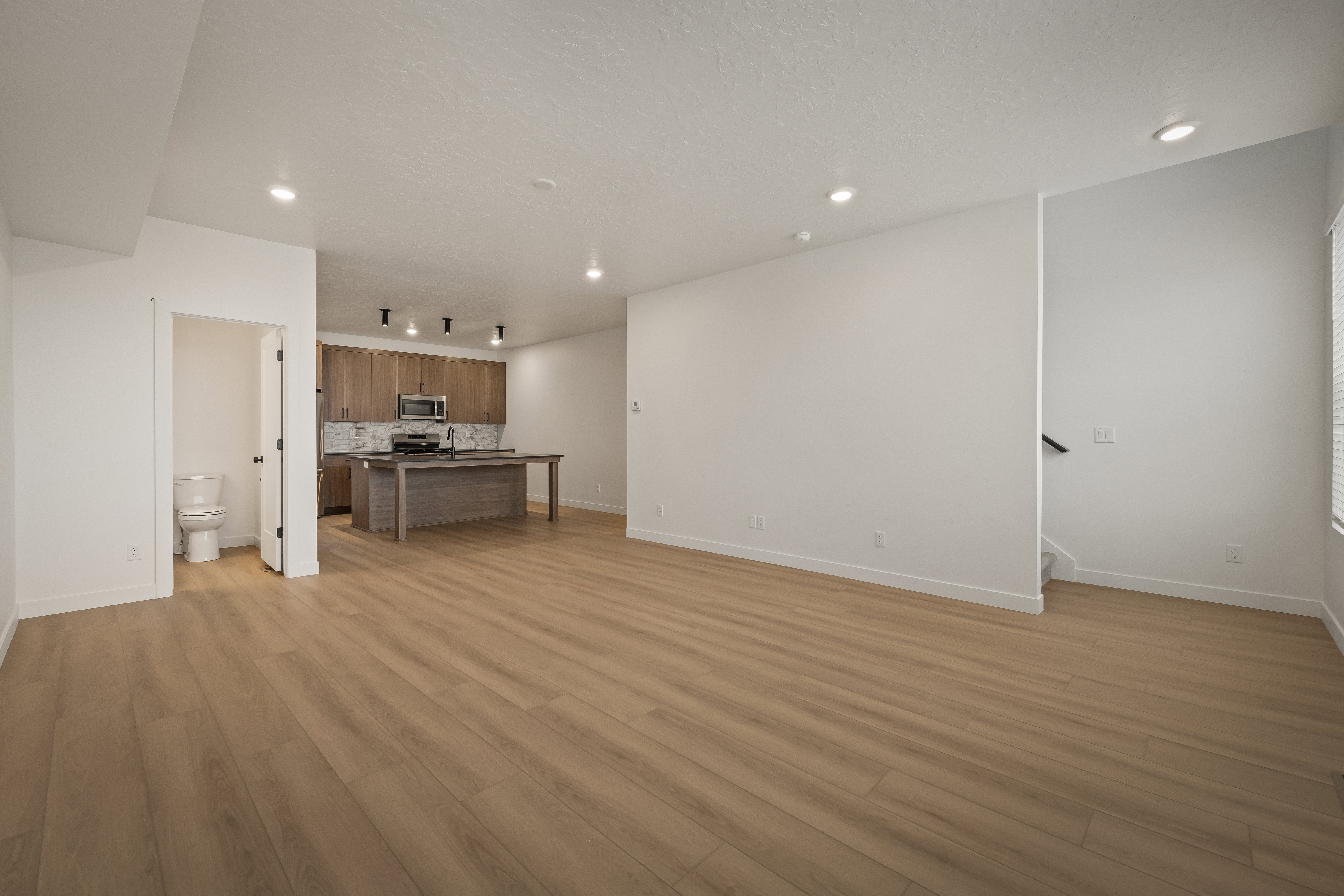 Spacious main living area featuring wood-finish flooring, recessed lighting, and a neutral color palette