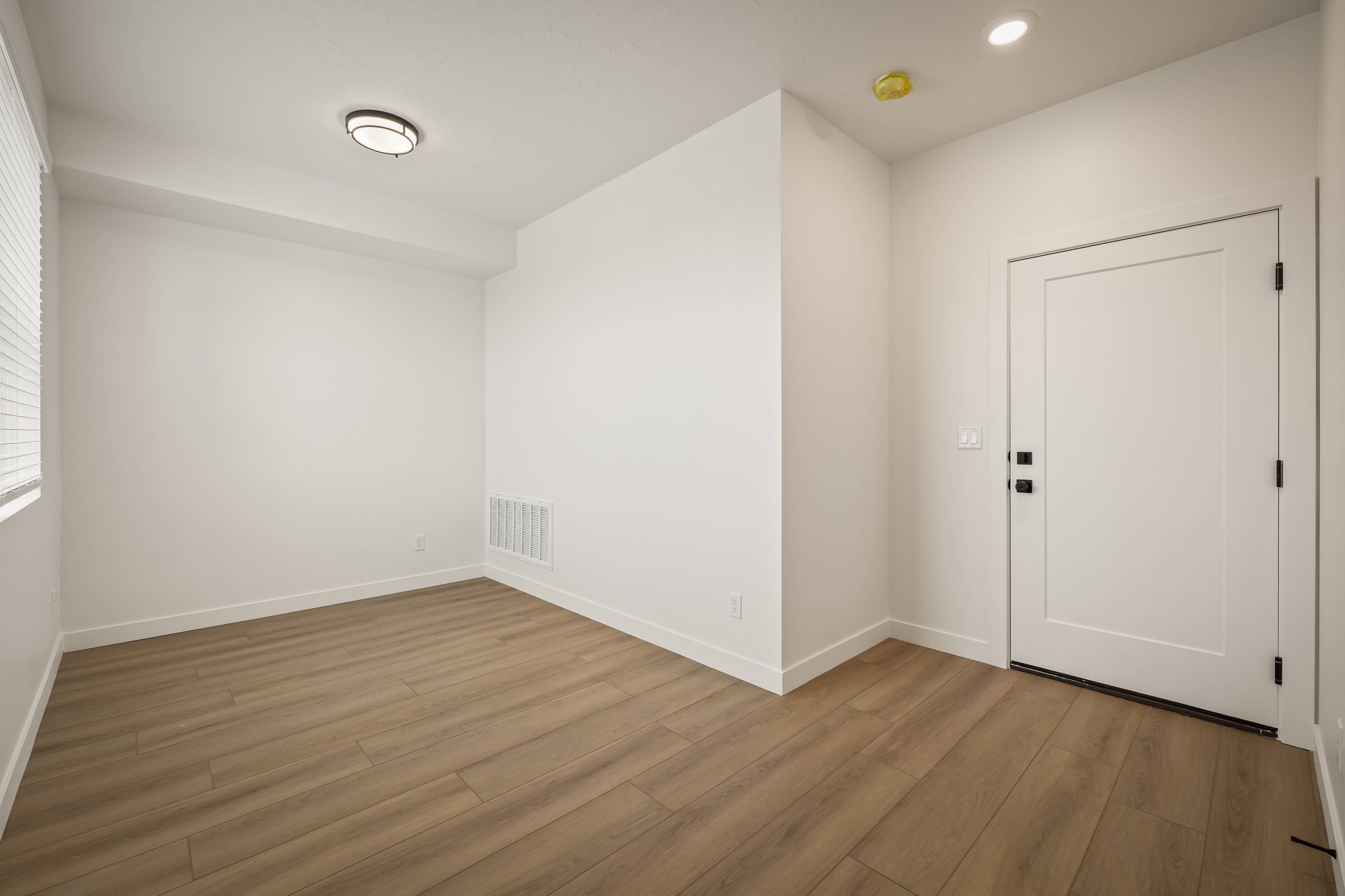 Bright interior space featuring wood-finish flooring, white walls, and a recessed ceiling light