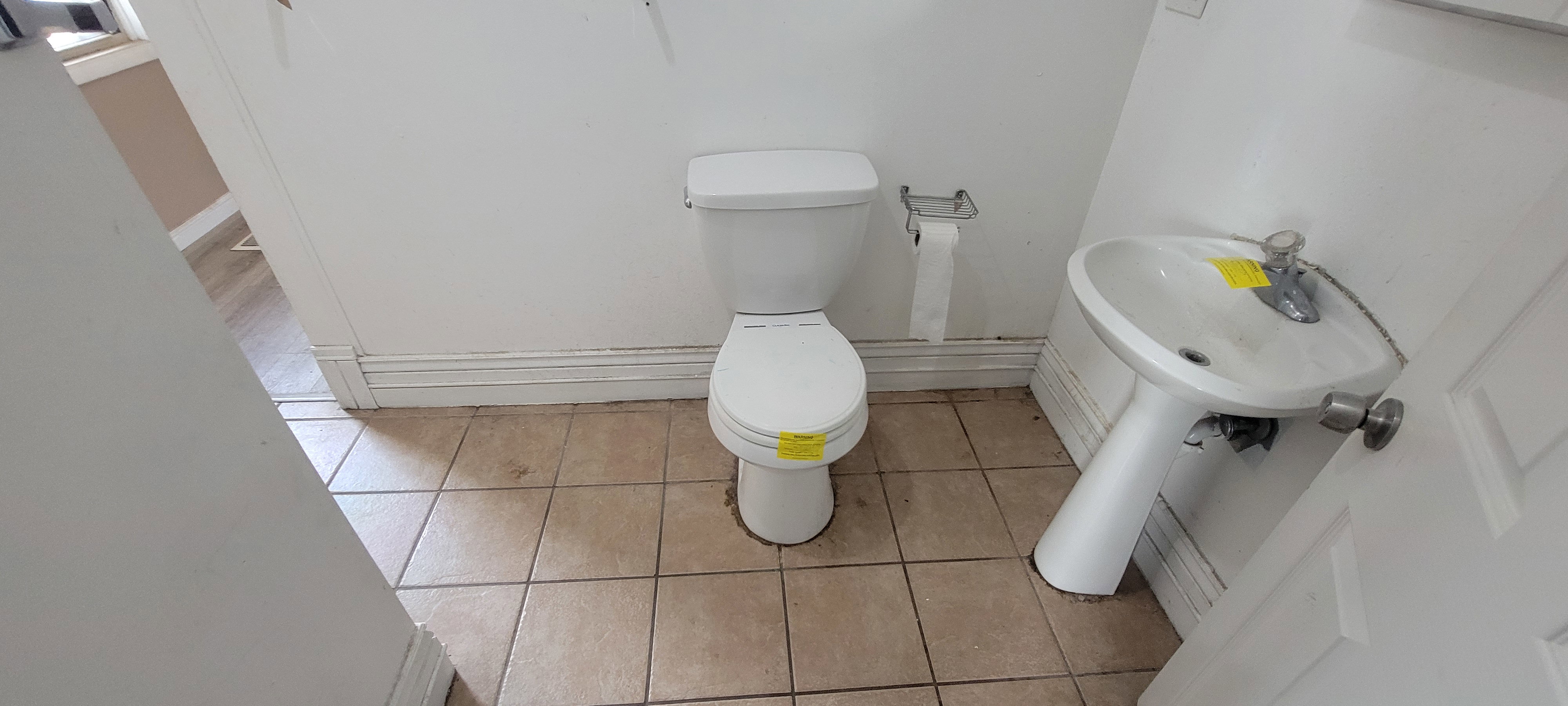 Restroom with ceramic tile flooring, a white pedestal sink, and a white two-piece toilet