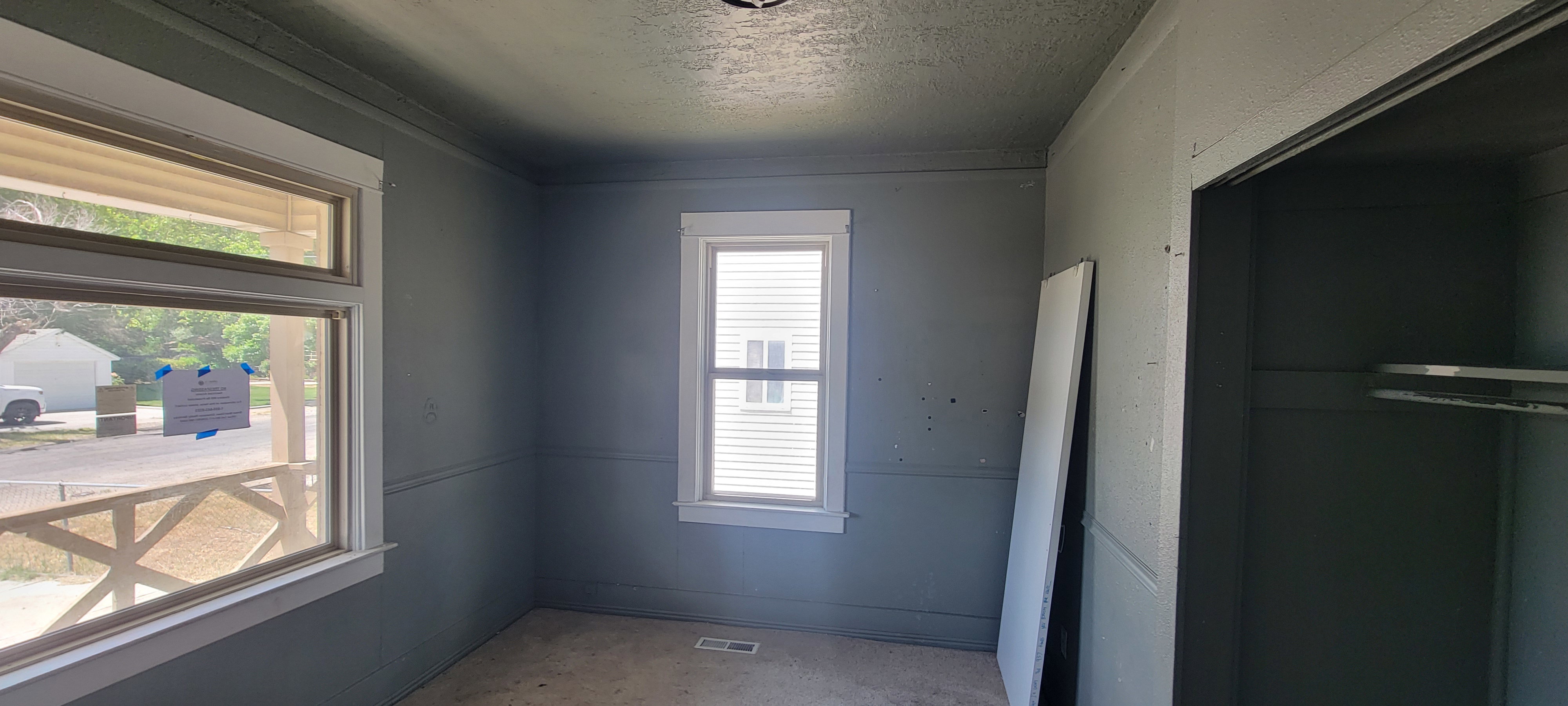 Room featuring multiple windows with white trim, gray painted walls with chair rail detailing, and a ceiling-mounted light fixture