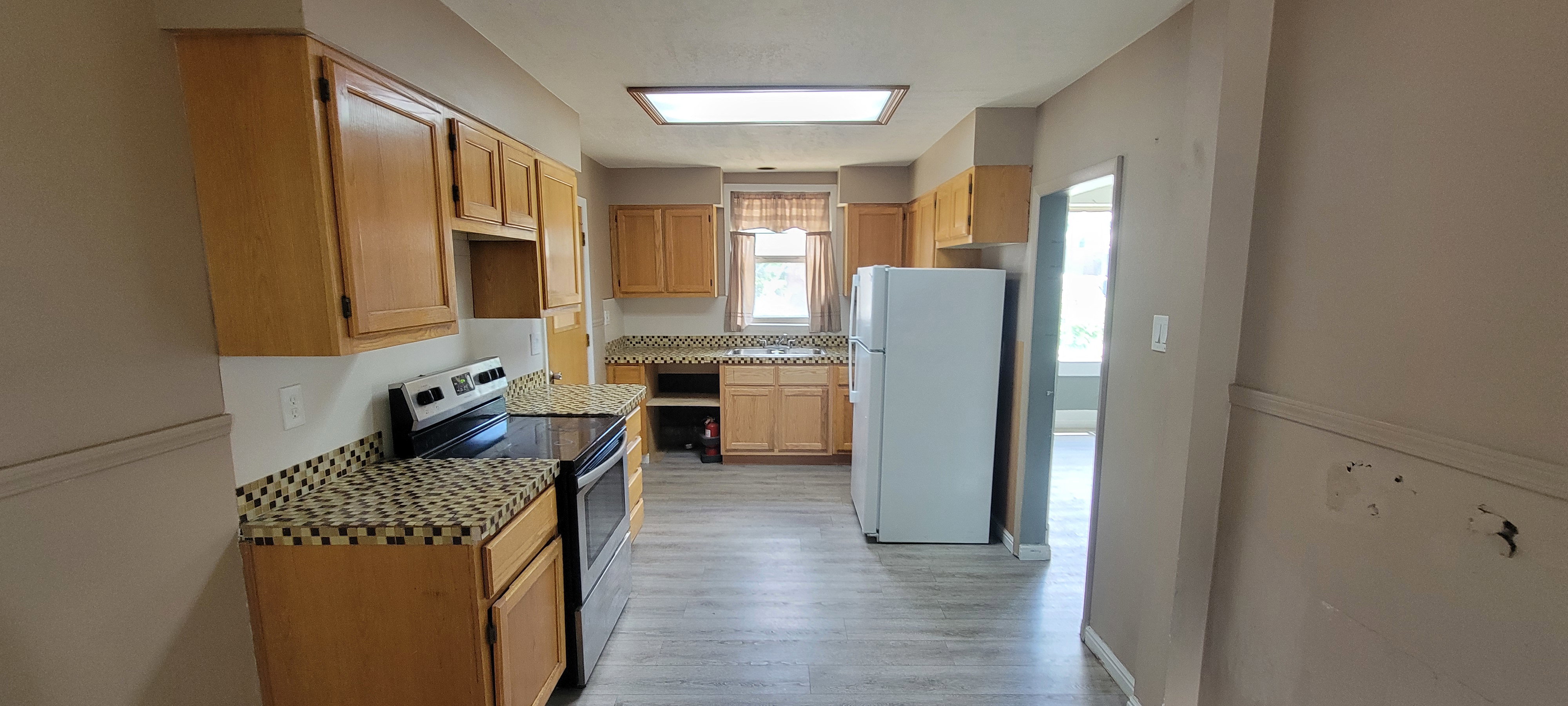 Kitchen featuring wood cabinetry, patterned countertops, and light wood-finish flooring