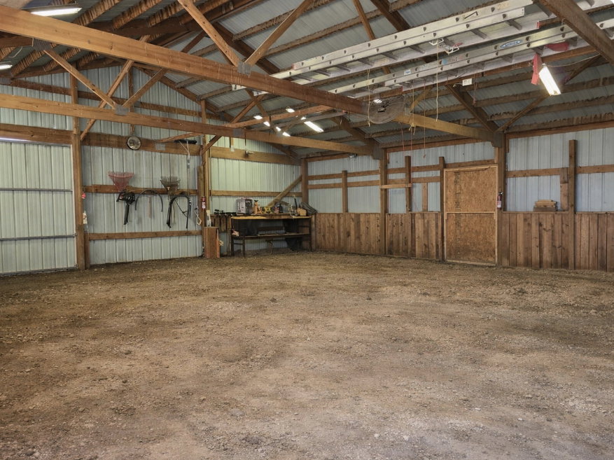 Spacious interior with exposed wood beam trusses and a corrugated metal roof