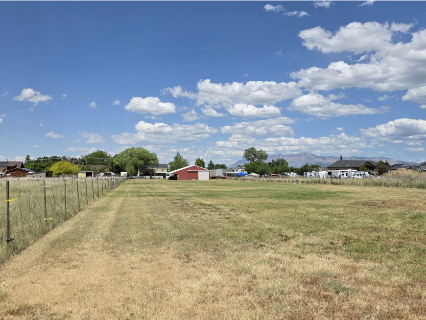 Expansive grassy lot with a wire fence lining the property boundary