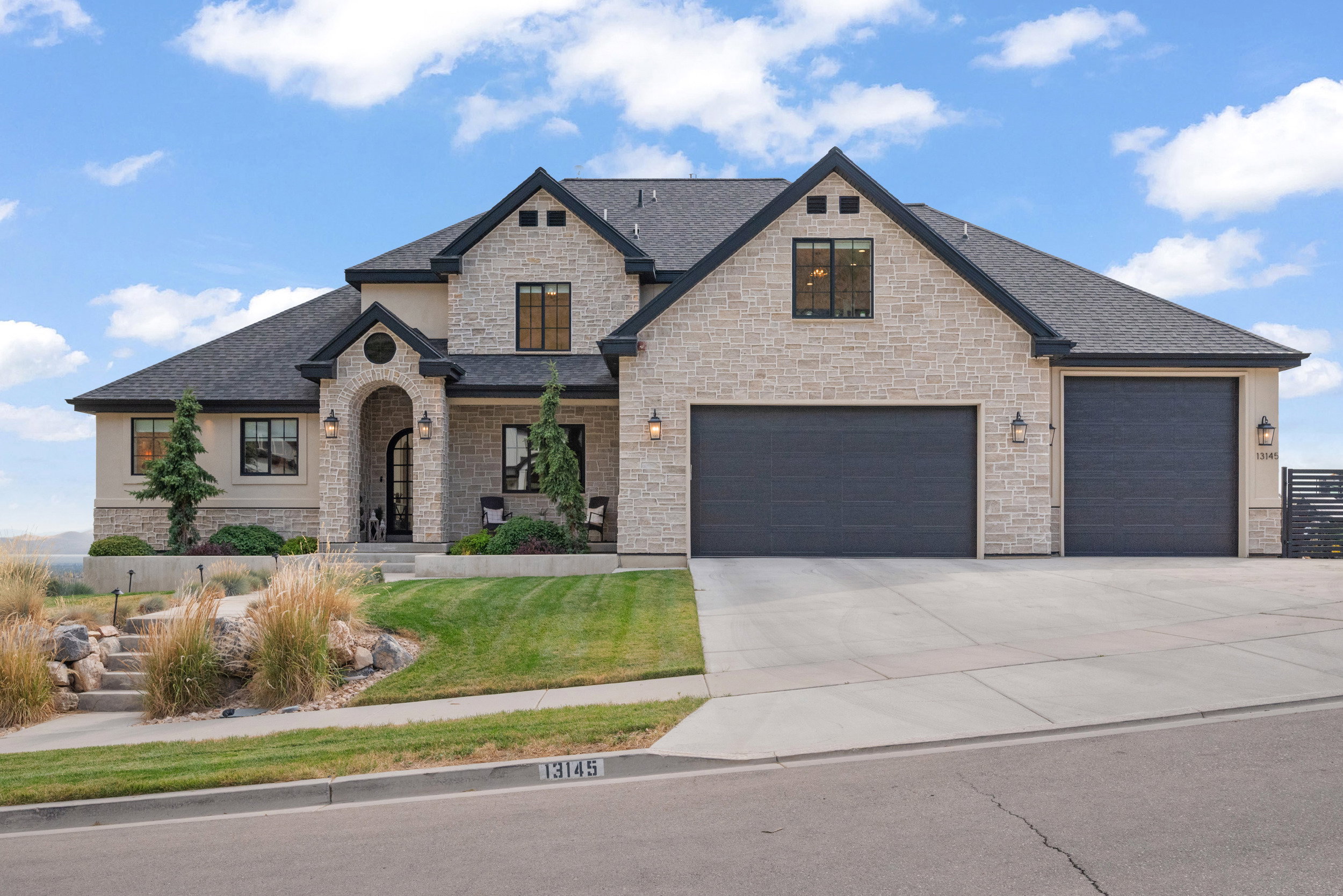 Stone and stucco exterior featuring multiple gables and a covered arched entryway
