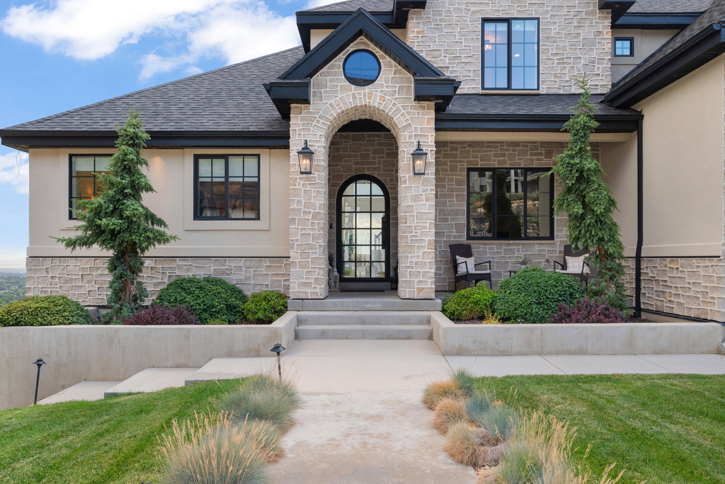Stone and stucco exterior with dark trim accents and a prominent arched entryway