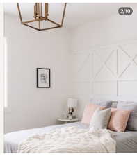 White bedroom featuring a decorative accent wall with geometric paneling