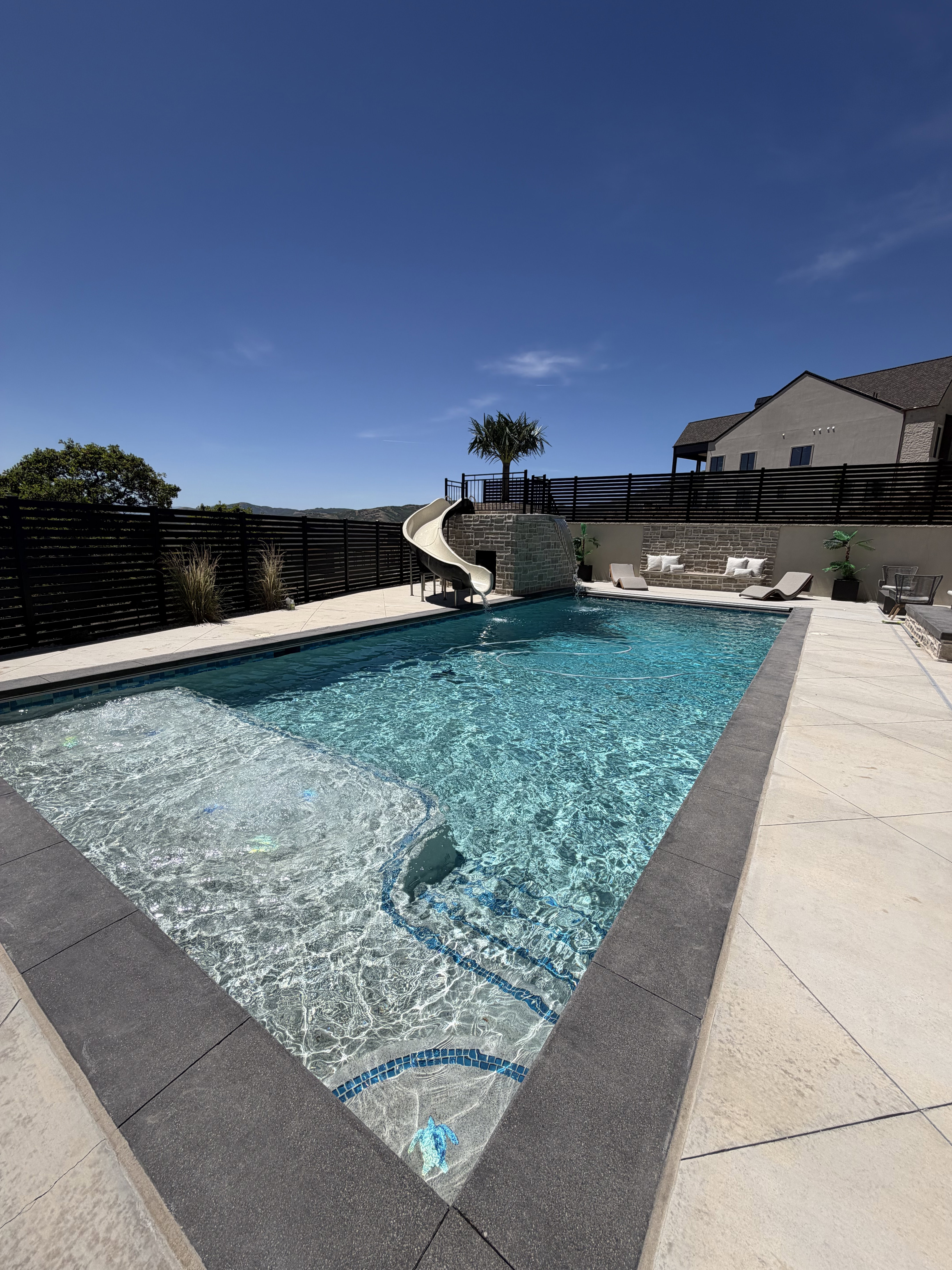 Rectangular swimming pool with a stone slide feature and integrated steps