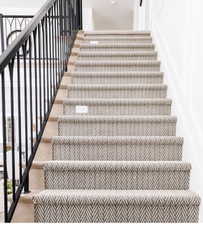 Staircase featuring a patterned runner, hardwood treads, white risers, and black metal balusters with an arched detail