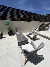 Outdoor patio featuring a rectangular fire pit with decorative stones, surrounded by light-toned pavers