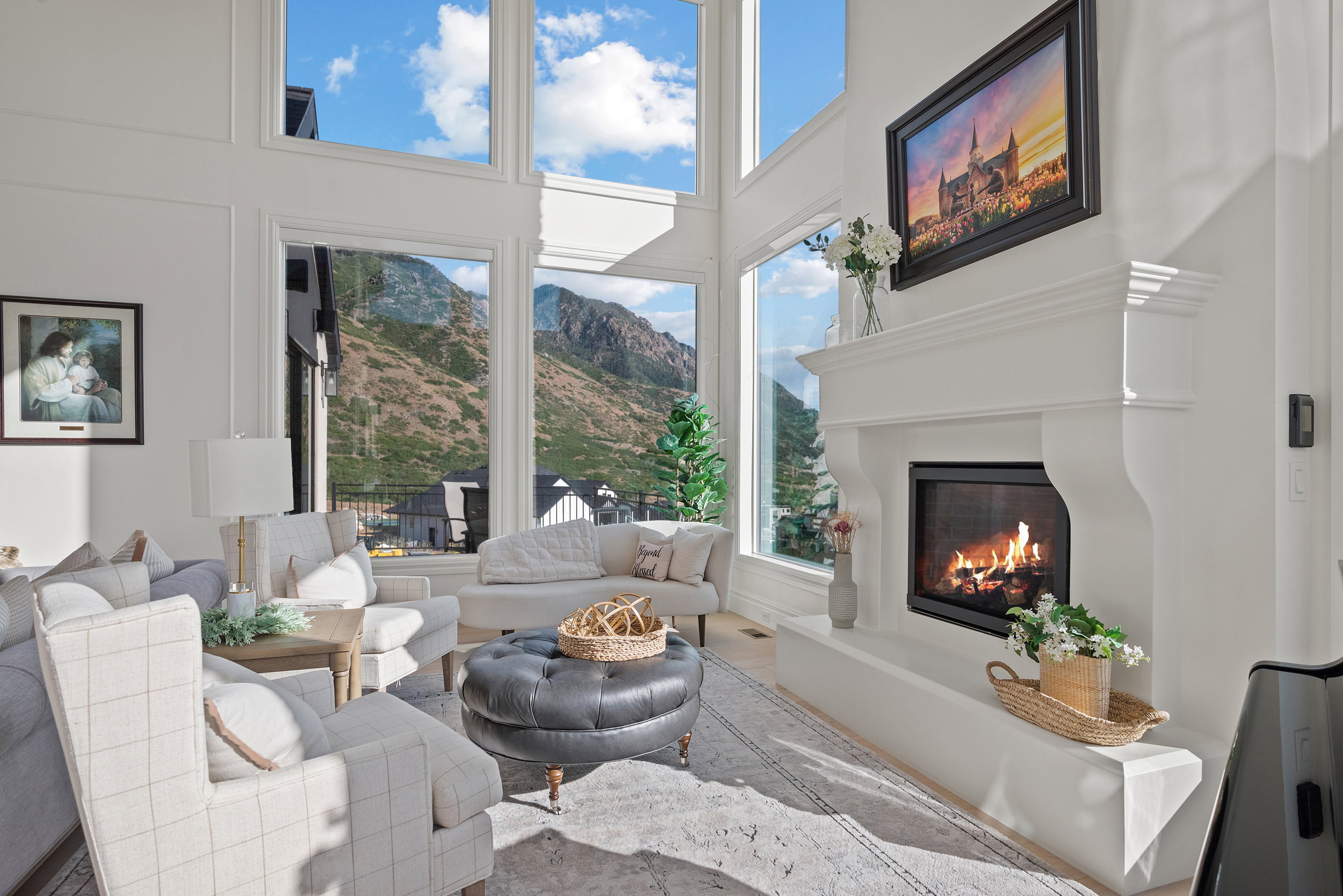 Living room featuring a prominent fireplace with a white mantel and hearth, soaring ceilings, and expansive picture windows