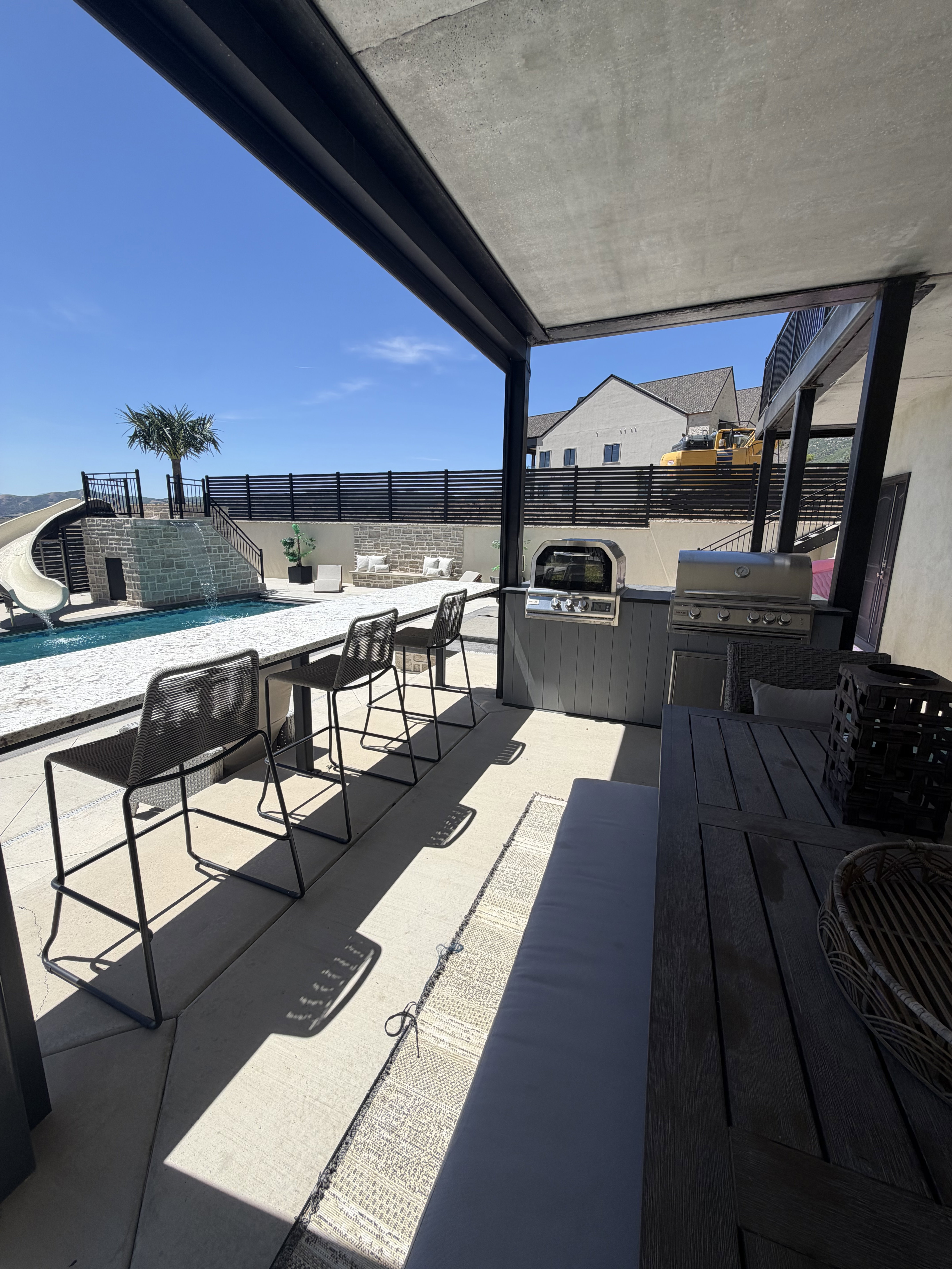Covered outdoor kitchen featuring a built-in grill and counter seating