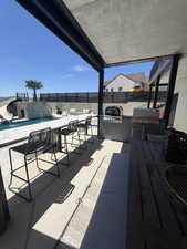 Covered outdoor kitchen featuring a built-in grill and counter seating