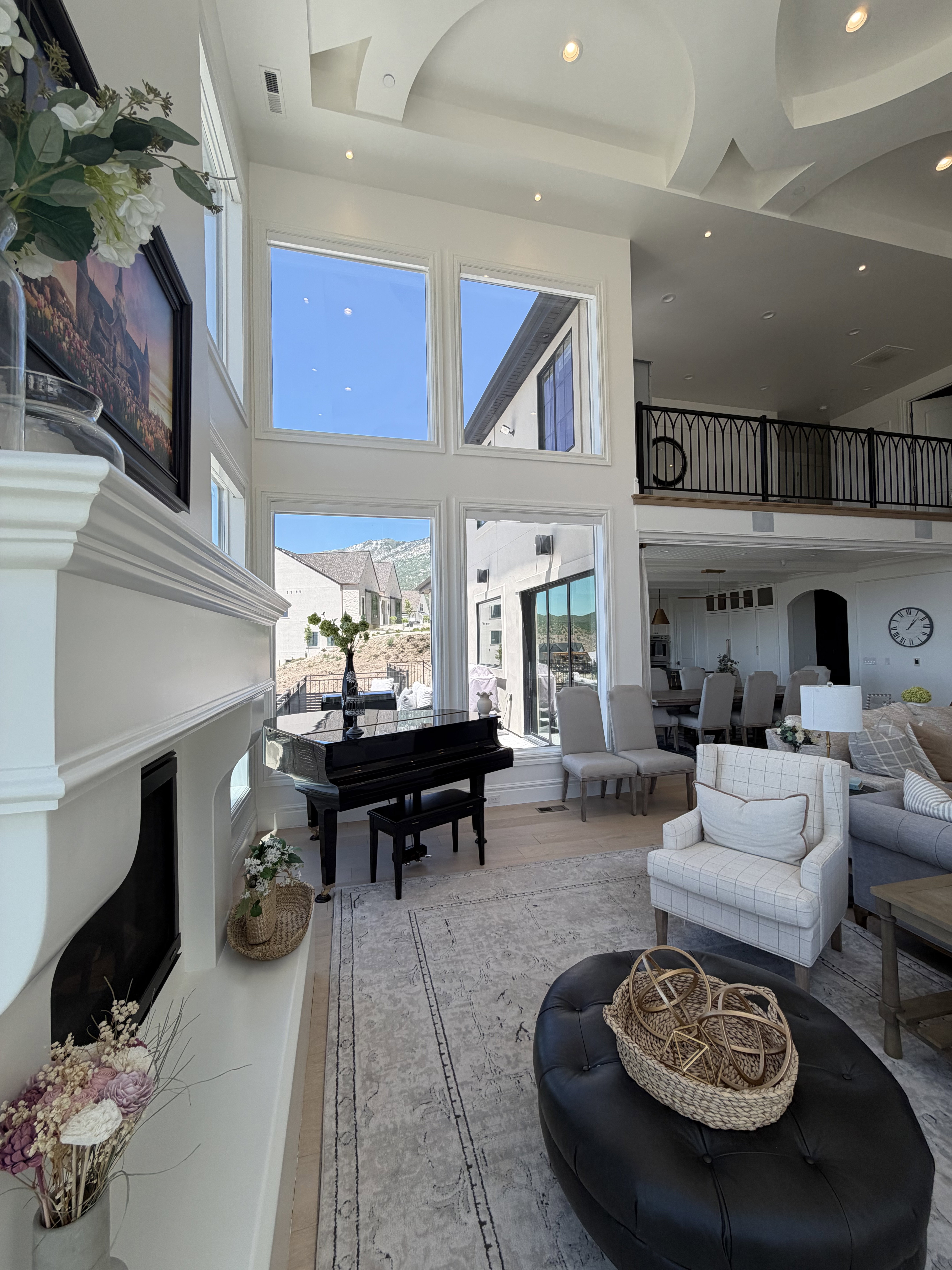 Two-story living area with multiple large windows, recessed lighting, and a decorative tray ceiling