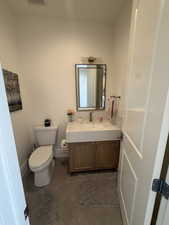 Bathroom featuring a wood-finish vanity with integrated sink, rectangular framed mirror, and contemporary wall-mounted light fixture