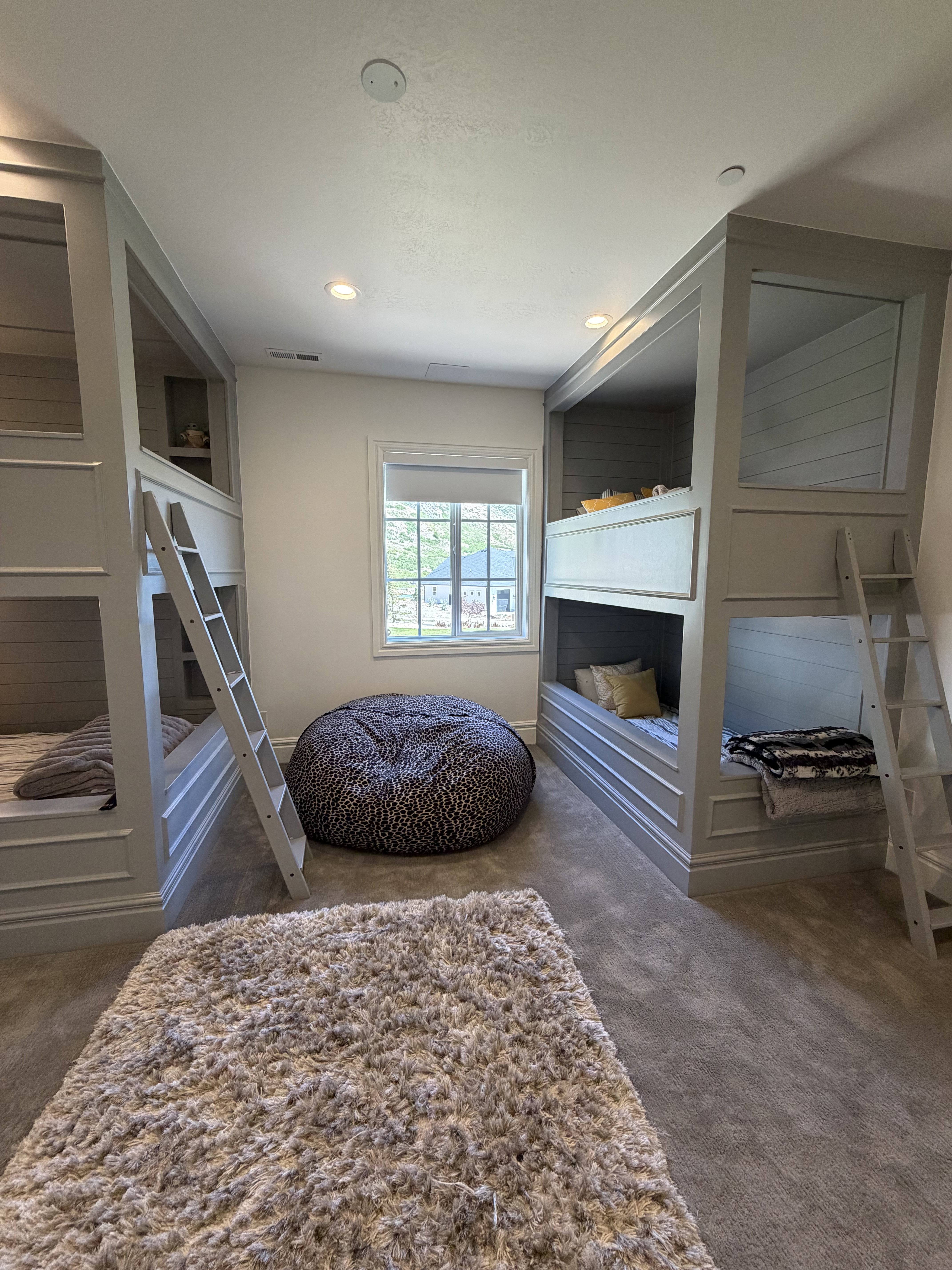Built-in bunk beds featuring a paneled design, integrated ladders, recessed lighting, and soft carpet flooring