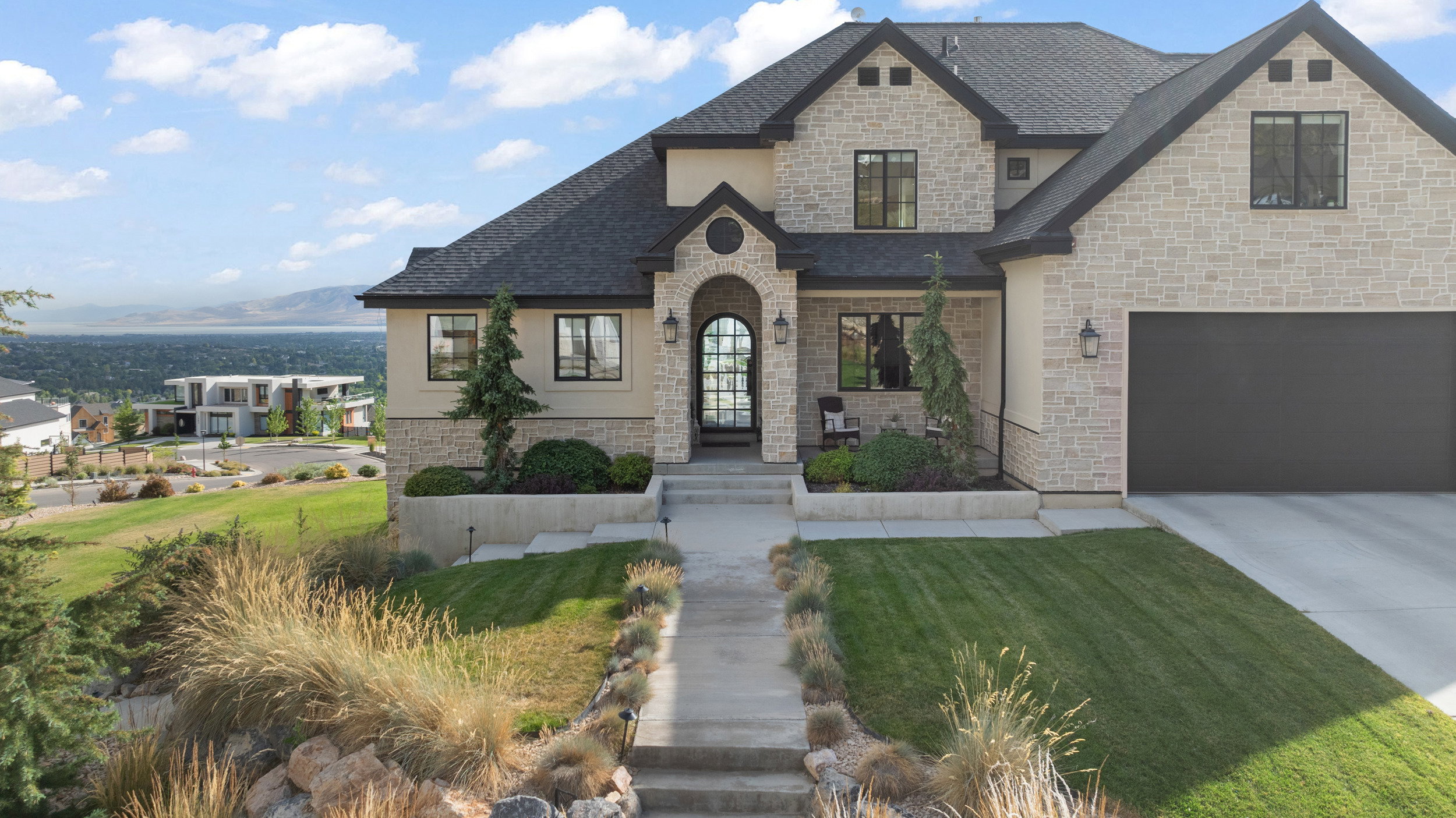 Stone and stucco exterior featuring a dark asphalt shingle roof