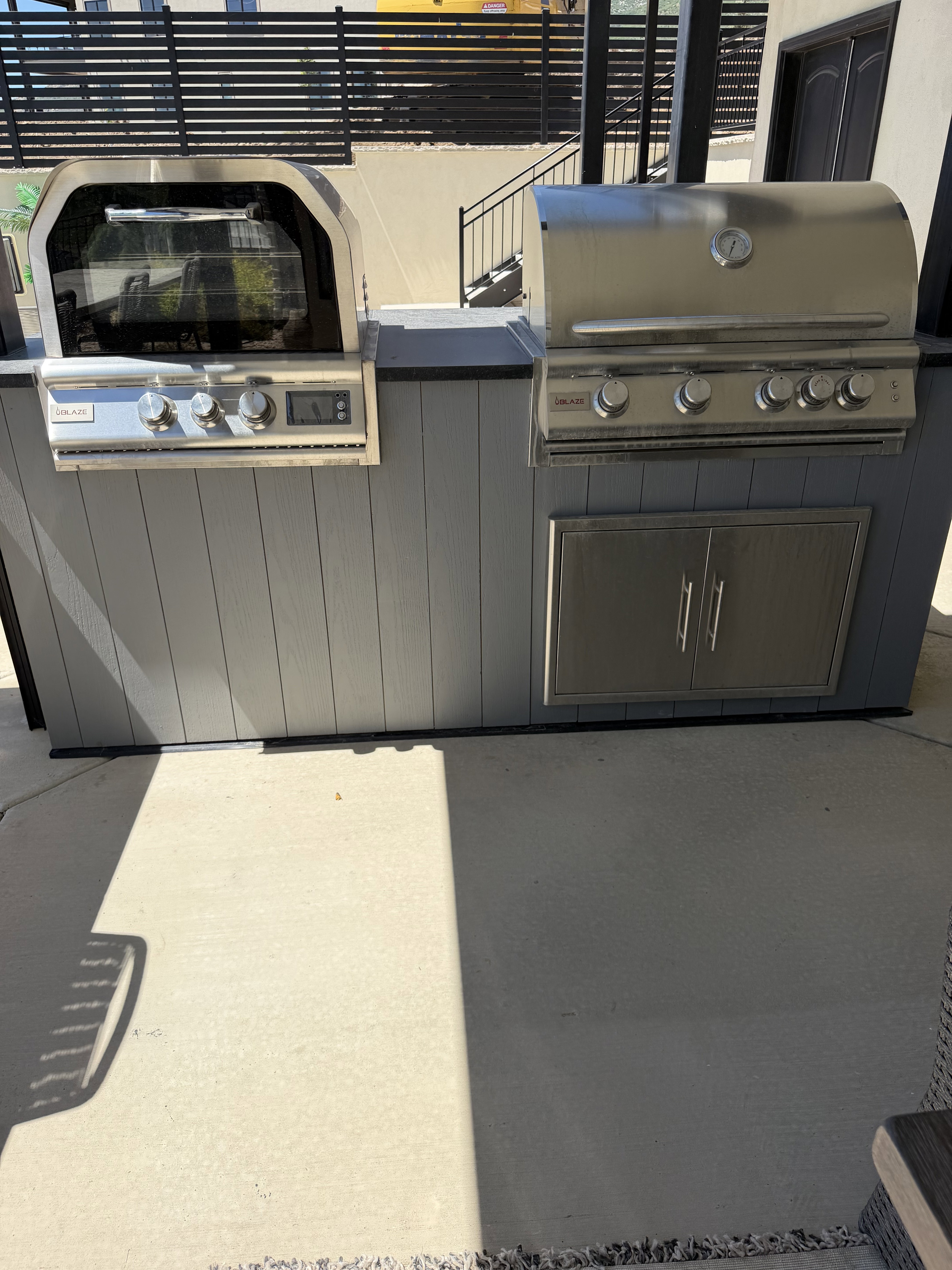 Outdoor kitchen featuring a built-in stainless steel grill, integrated oven, and stainless steel cabinet storage