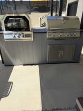 Outdoor kitchen featuring a built-in stainless steel grill, integrated oven, and stainless steel cabinet storage