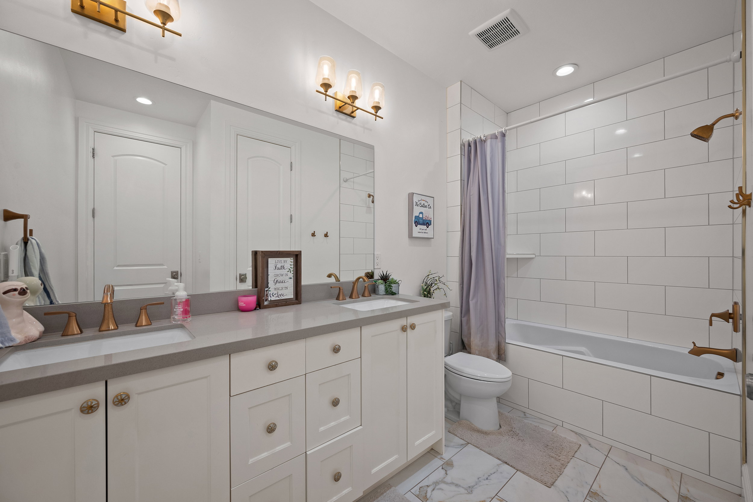 Bathroom featuring a dual vanity with light gray countertops and white cabinetry