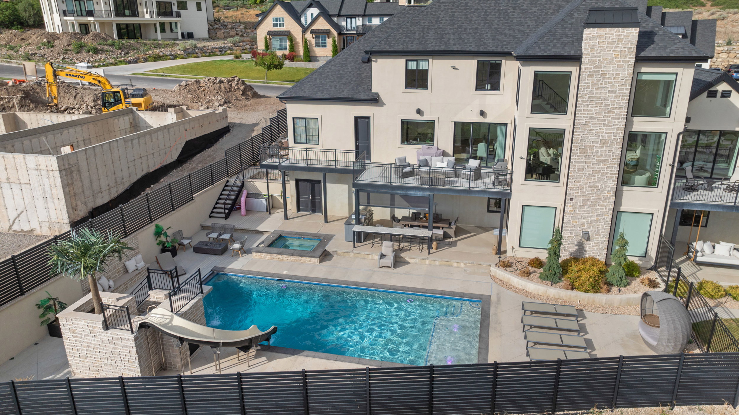 Expansive backyard oasis featuring a large swimming pool with slide, integrated hot tub, and multiple outdoor entertaining areas
