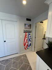 Recessed ceiling lighting illuminates a white honeycomb tile floor
