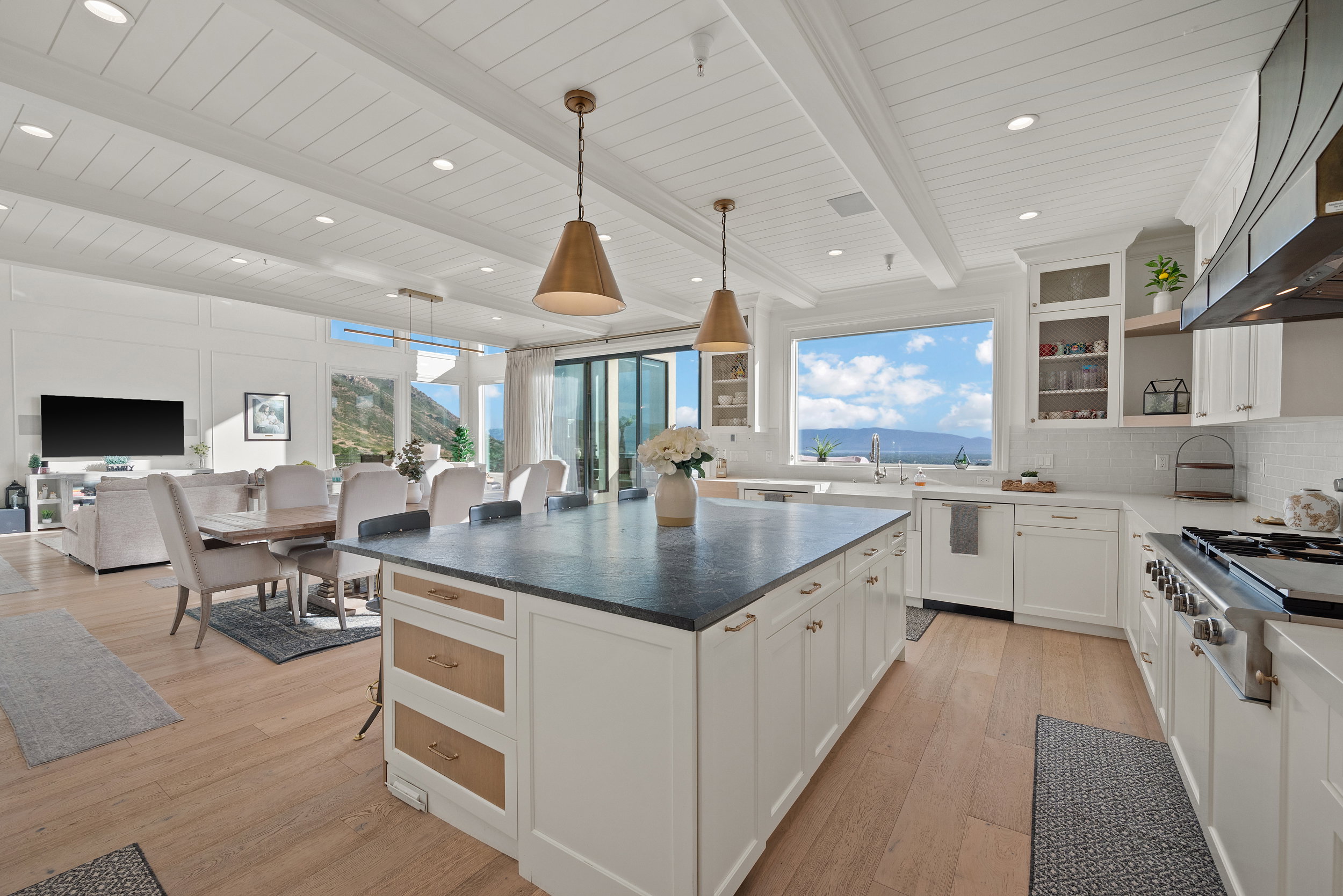 Open-concept living space featuring wood-finish flooring, a white coffered ceiling, and a kitchen island with a dark countertop