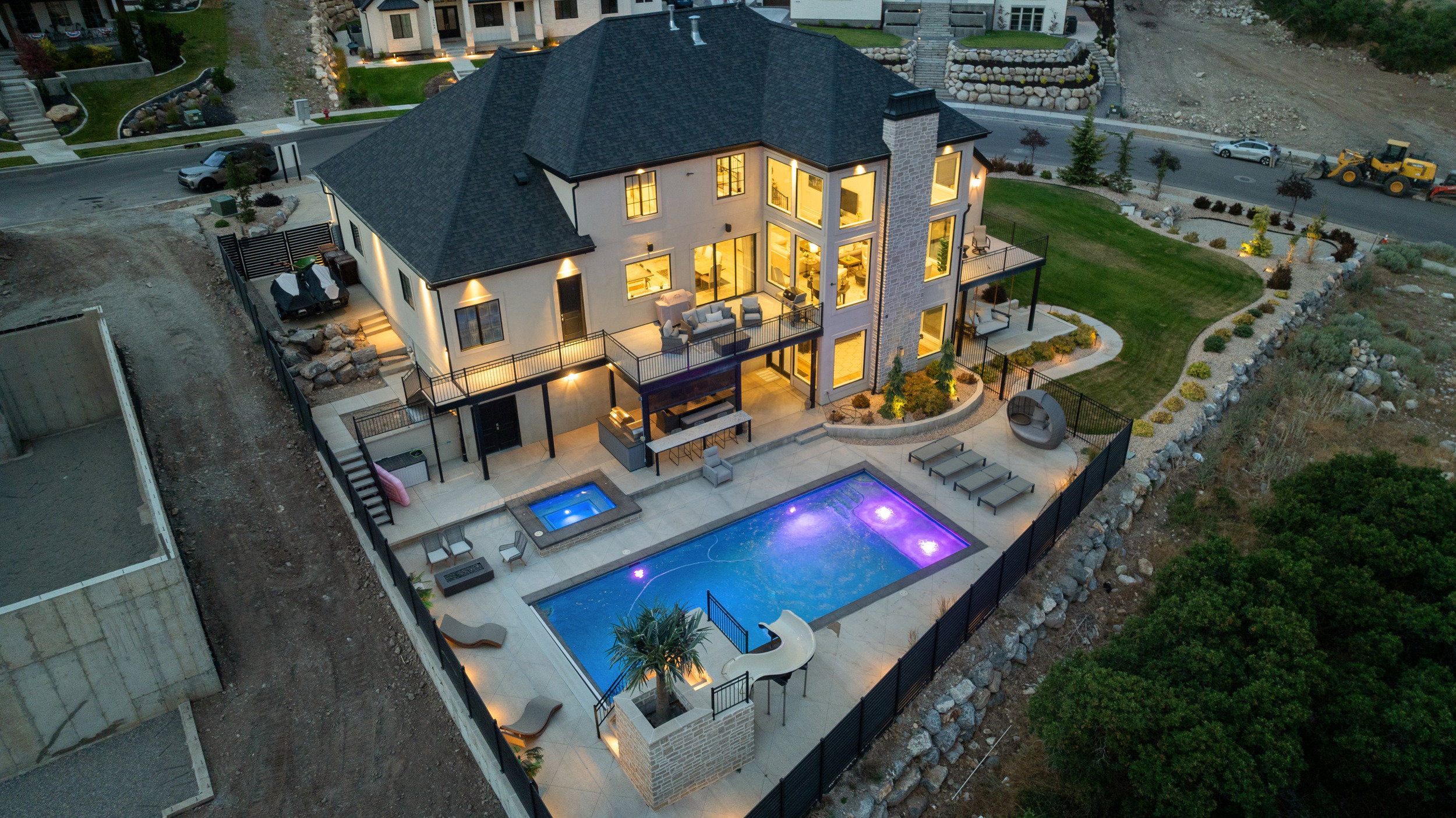 Multi-level residence featuring a dark shingle roof, light-colored siding, and extensive window arrays
