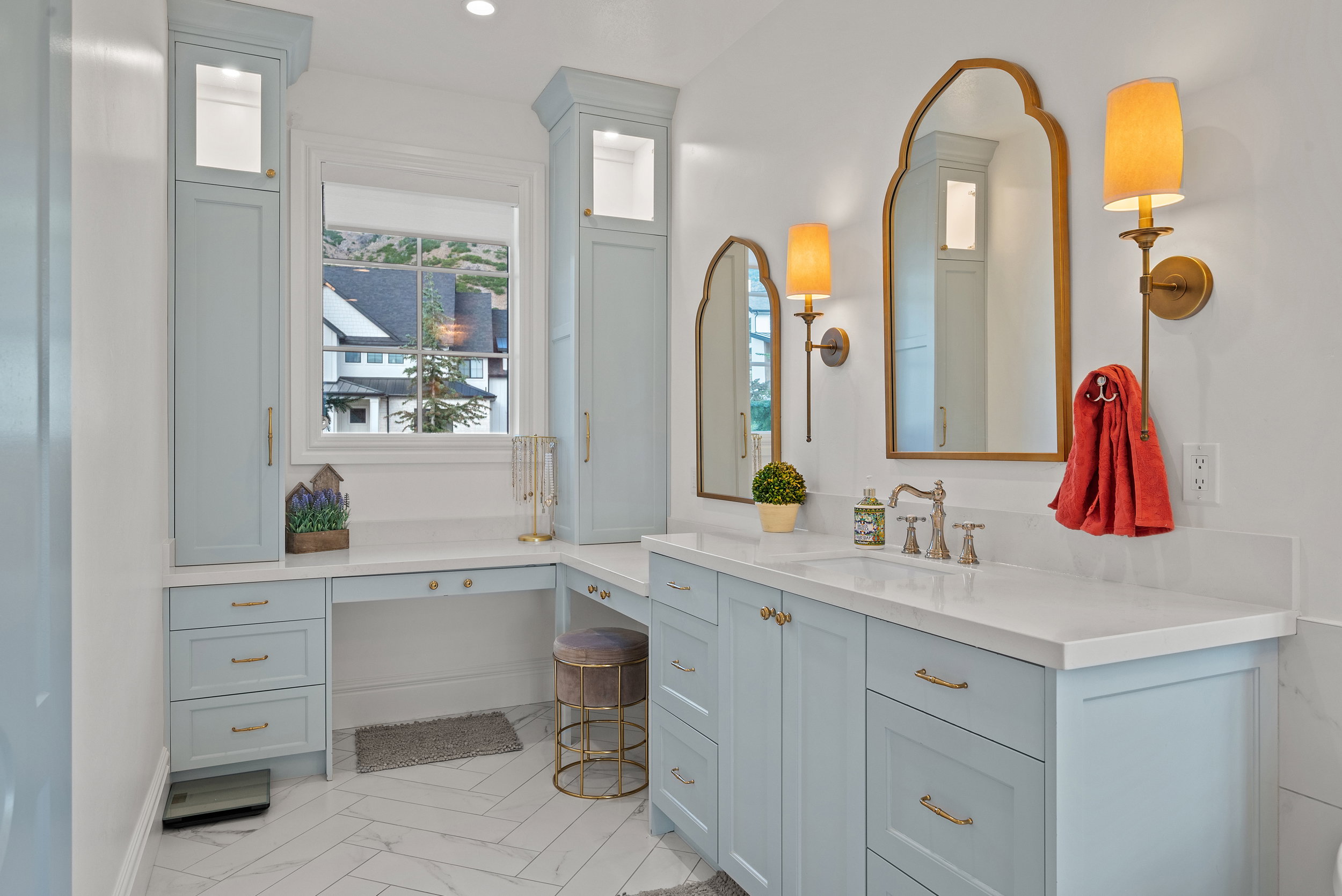 Bathroom featuring light blue cabinetry, dual gold-framed arched mirrors, and white countertops