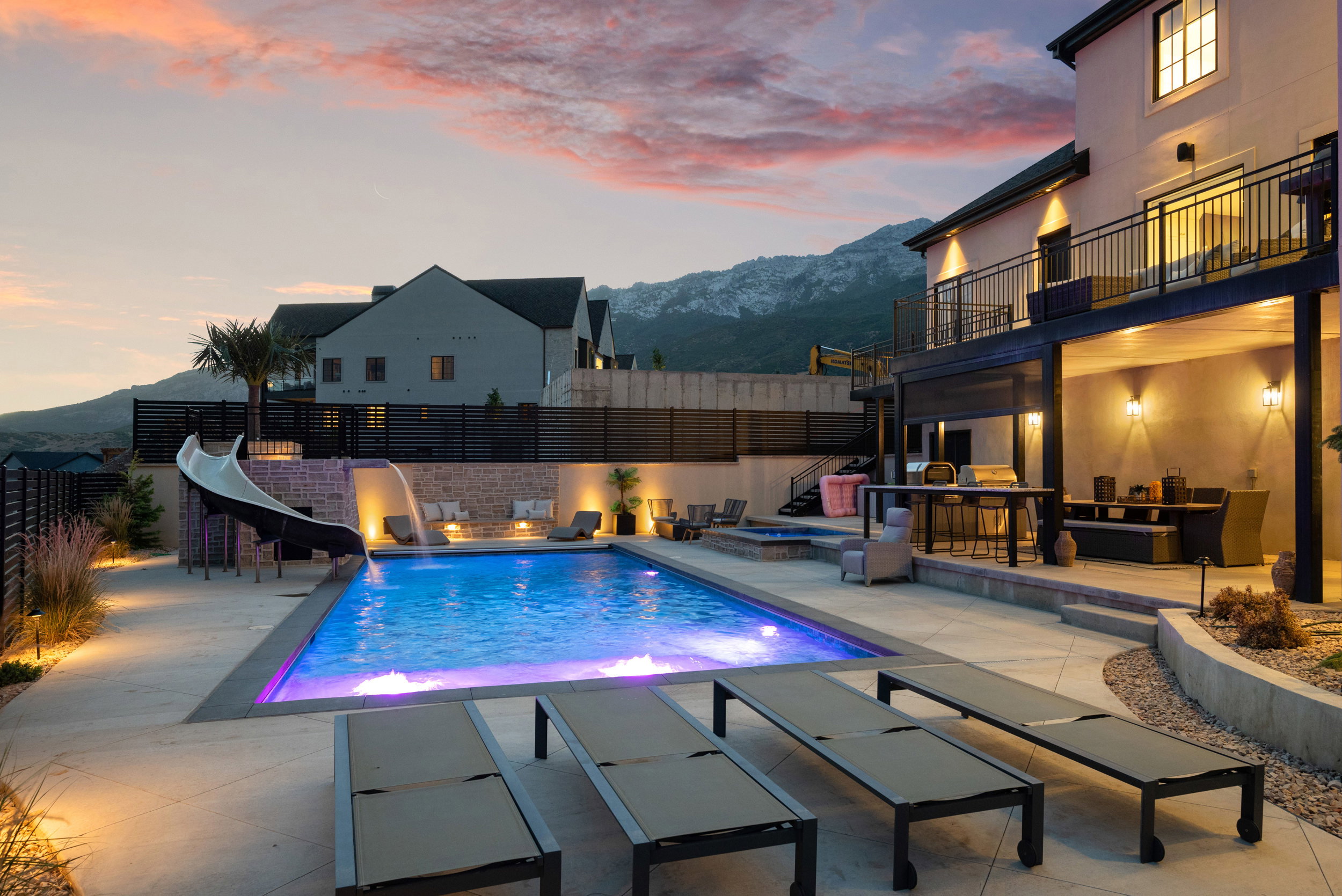 Expansive backyard featuring an in-ground swimming pool with integrated slide and illuminated water features