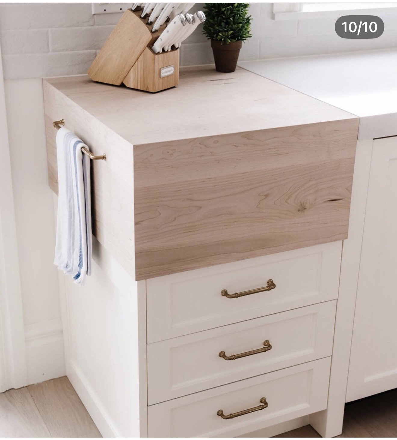 Light wood-finish countertop featuring a brass towel bar