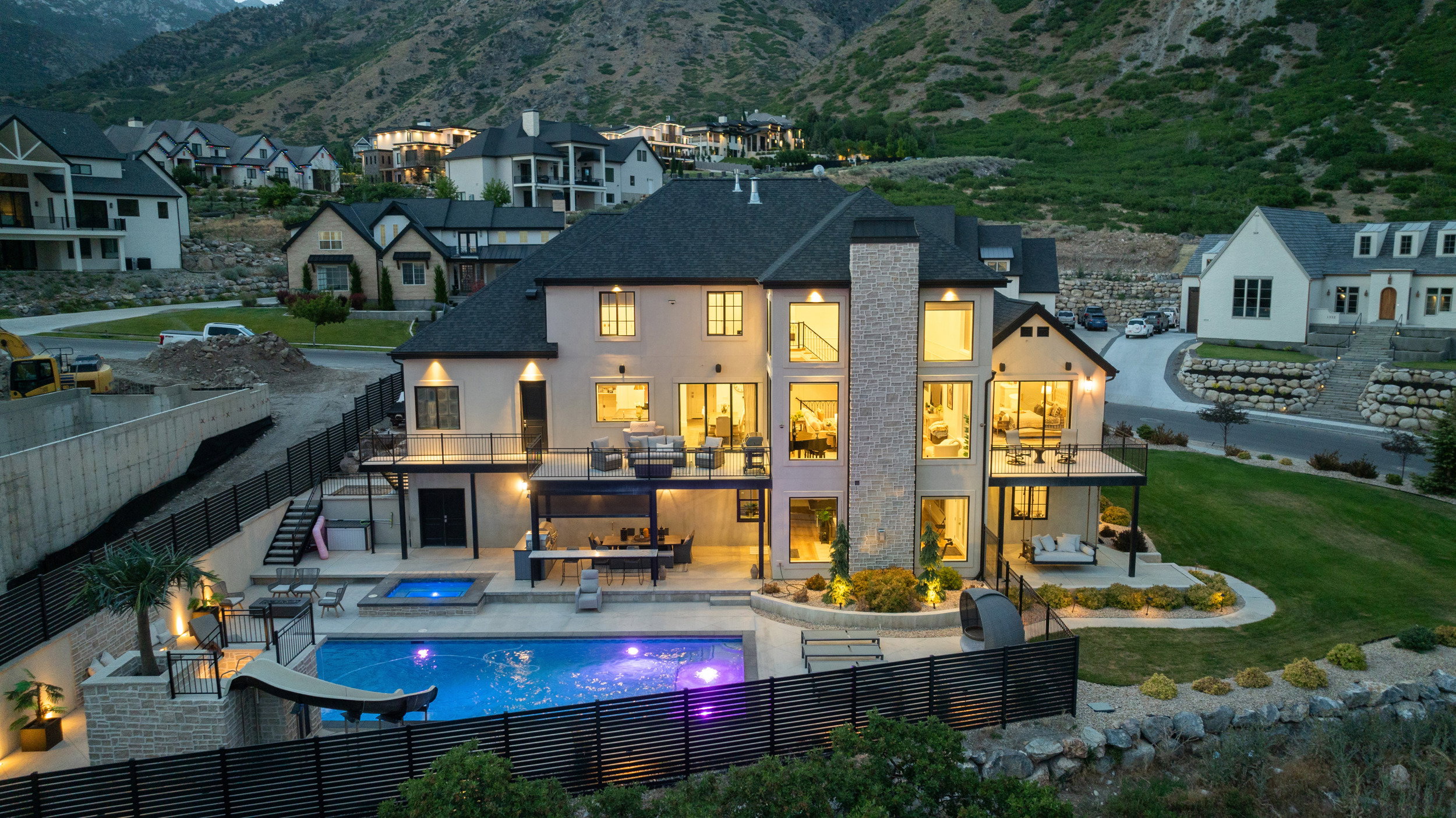 Multi-story residence featuring a stone and stucco exterior, dark shingle roofing, and numerous large windows