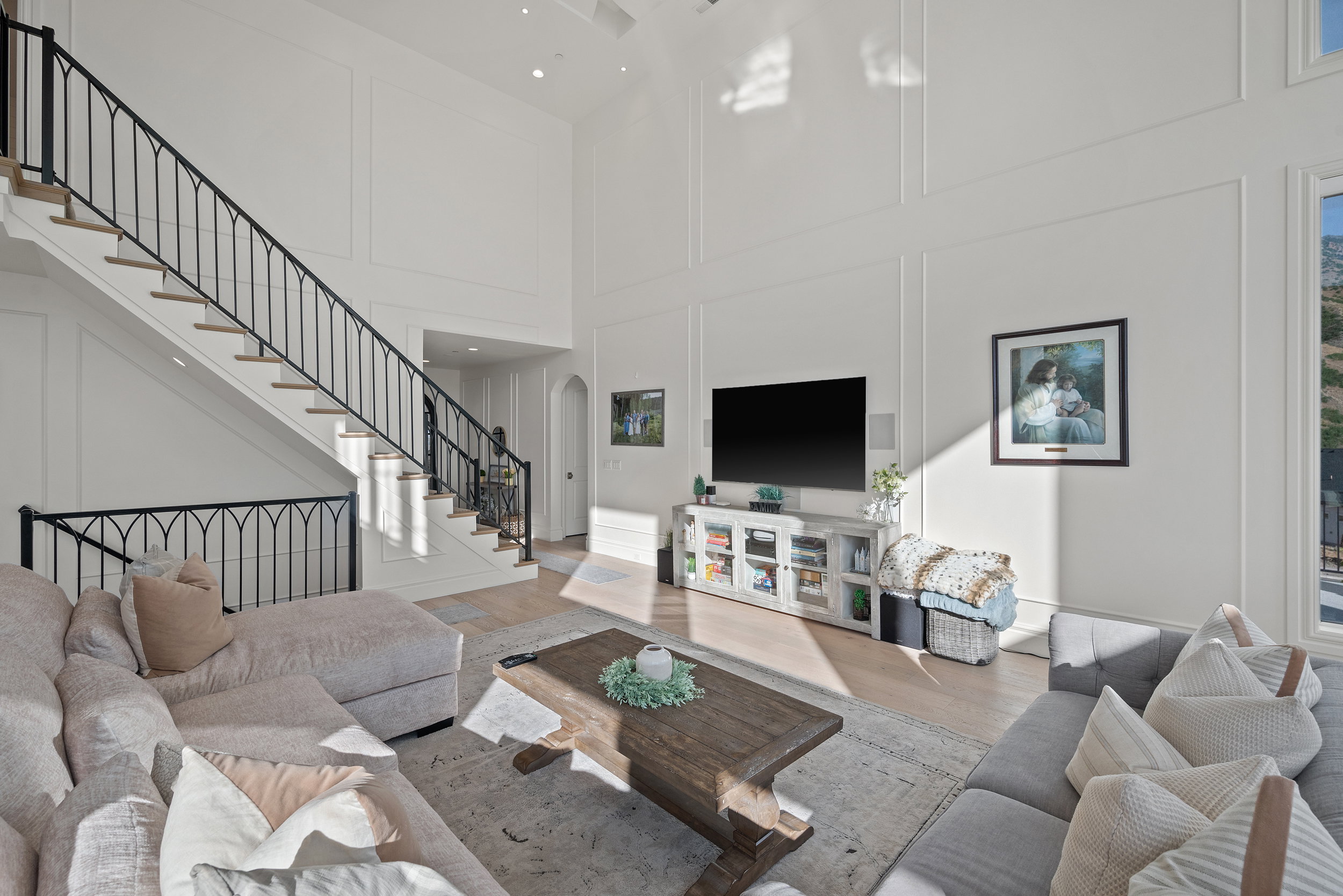 Two-story living area featuring a grand staircase with wrought iron balusters, recessed lighting, and wall paneling