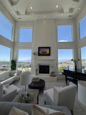 Two-story living room featuring a recessed ceiling, expansive windows, a fireplace with a mantel, and recessed lighting
