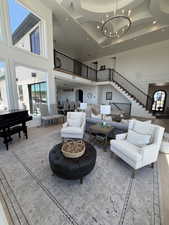 Grand living space featuring high ceilings, a decorative coffered ceiling detail, and a large circular chandelier
