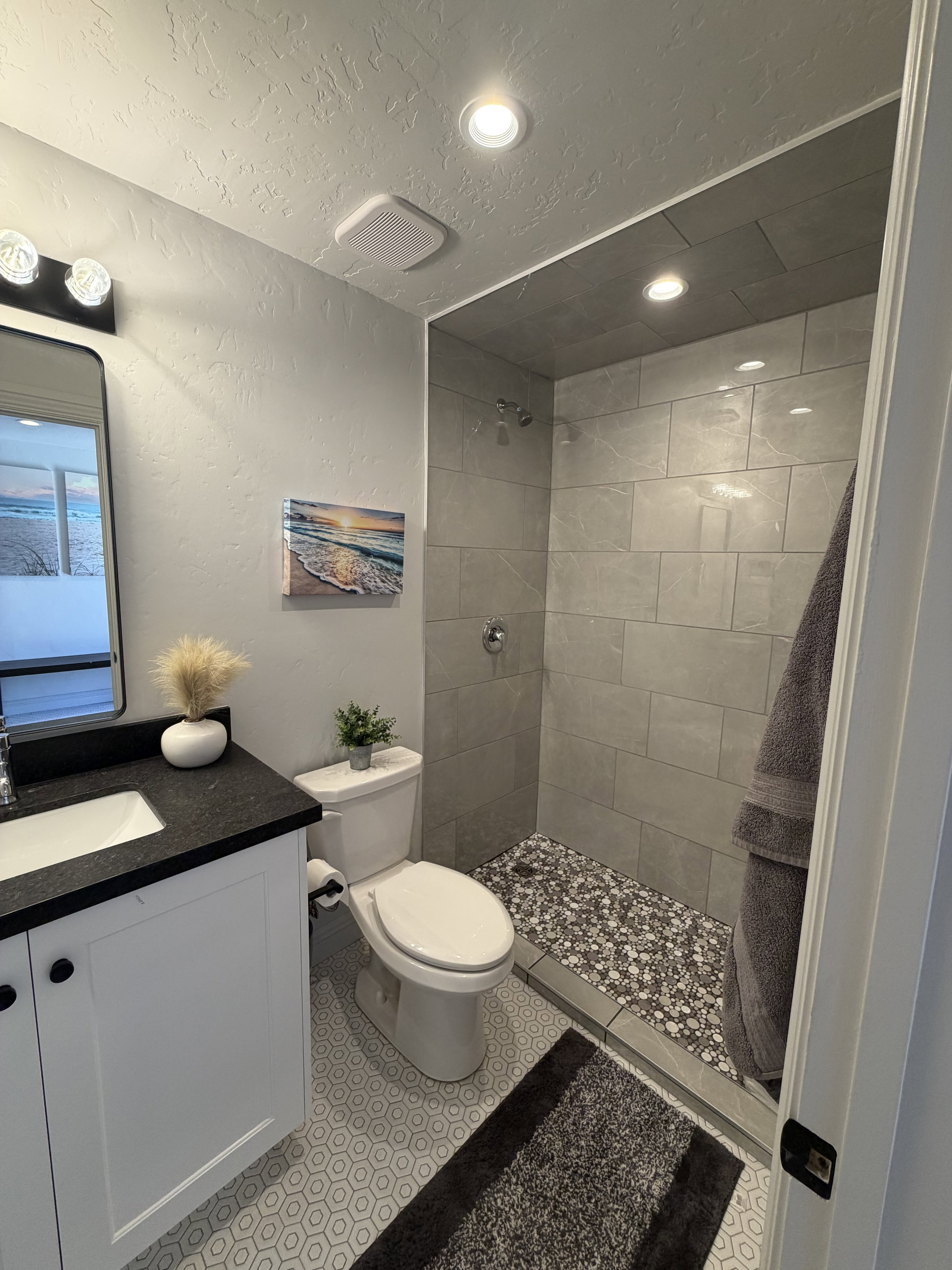 Contemporary bathroom featuring a walk-in shower with pebble tile flooring and large format wall tiles