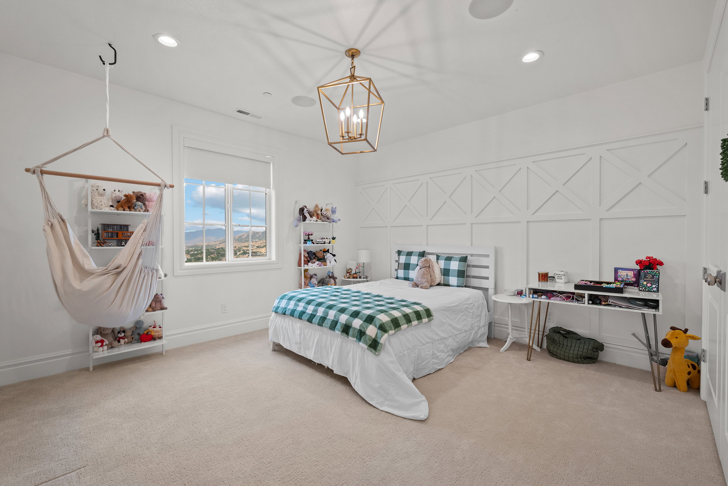 Bright interior space featuring a window with expansive distant scenery, recessed ceiling lighting, a decorative chandelier, and a paneled accent wall
