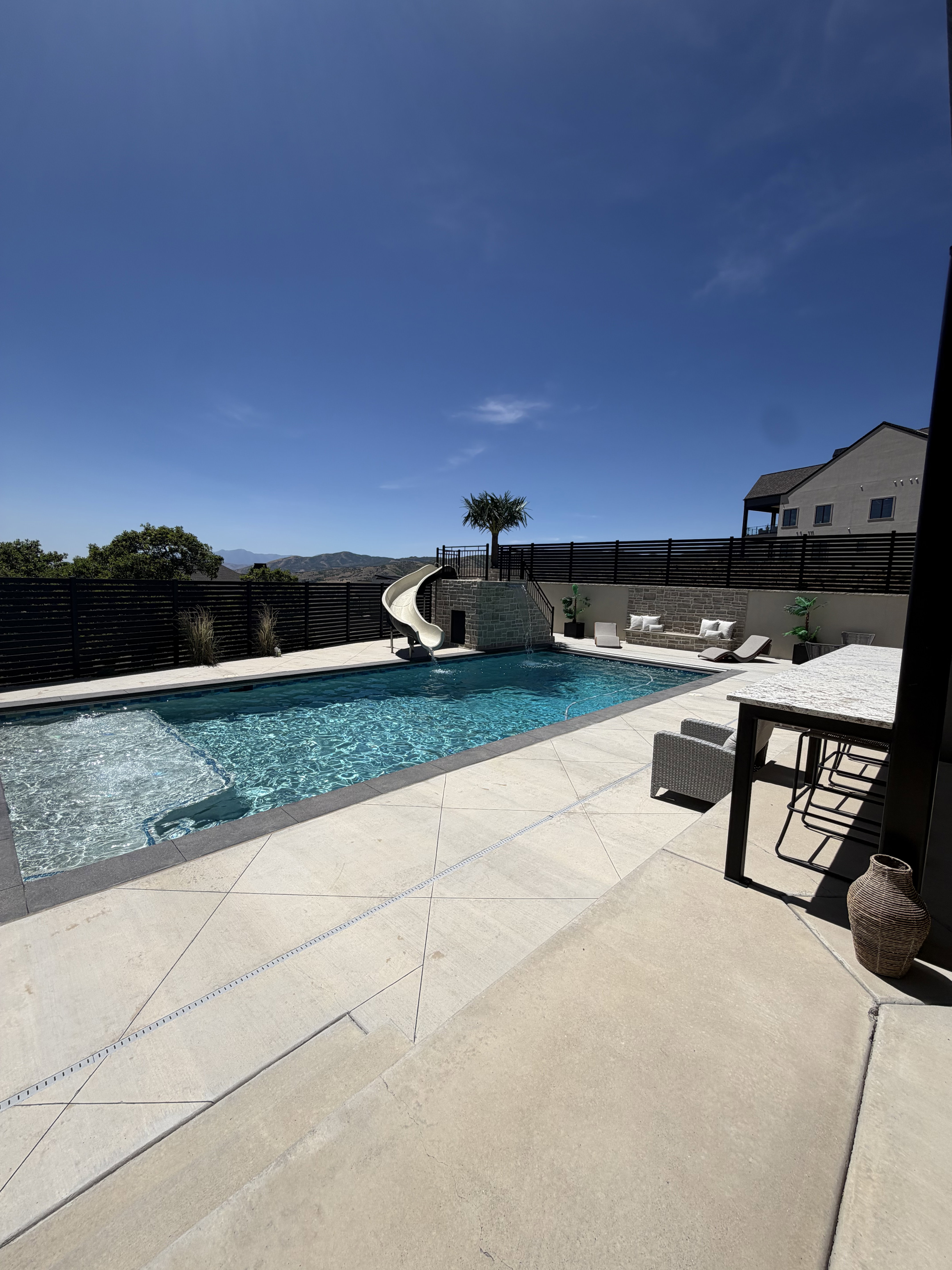 Expansive backyard featuring a custom swimming pool with integrated slide and water features