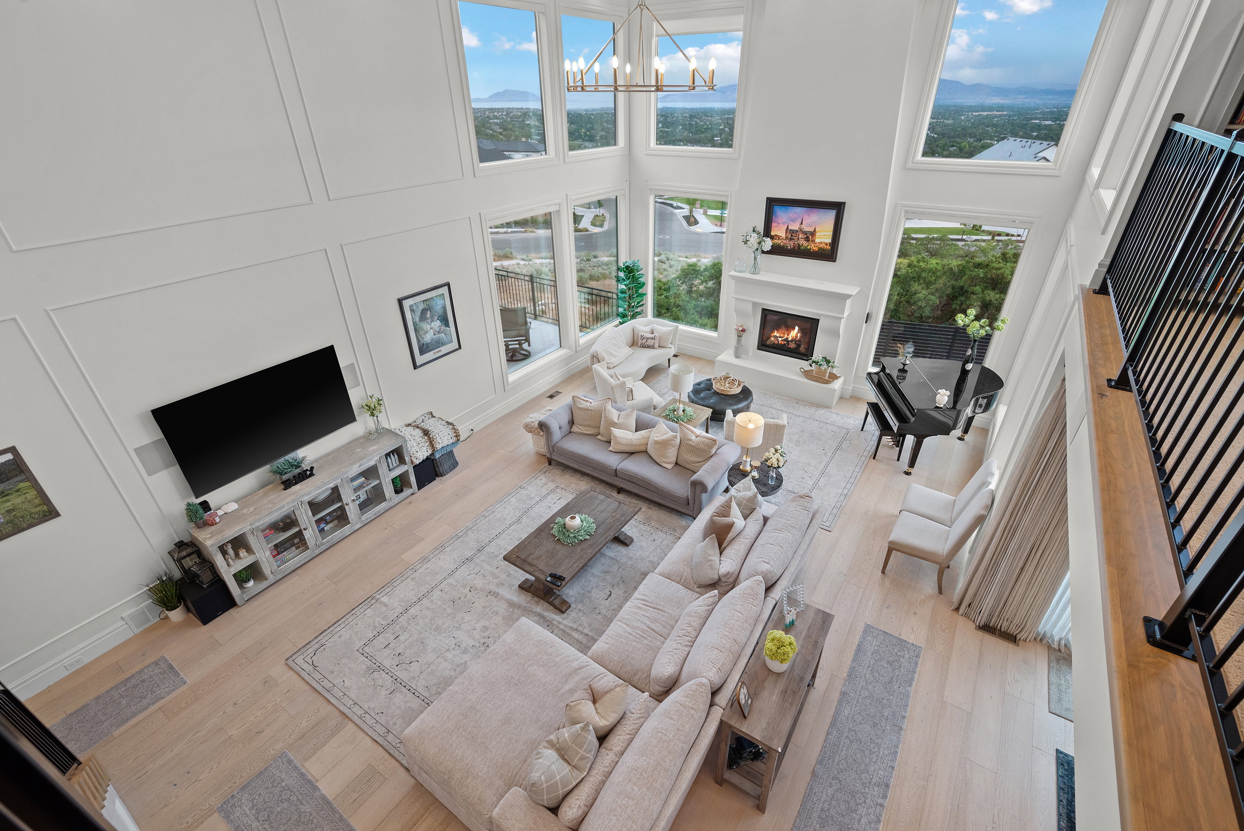 Two-story living area with soaring ceilings, a fireplace with mantel, and large windows