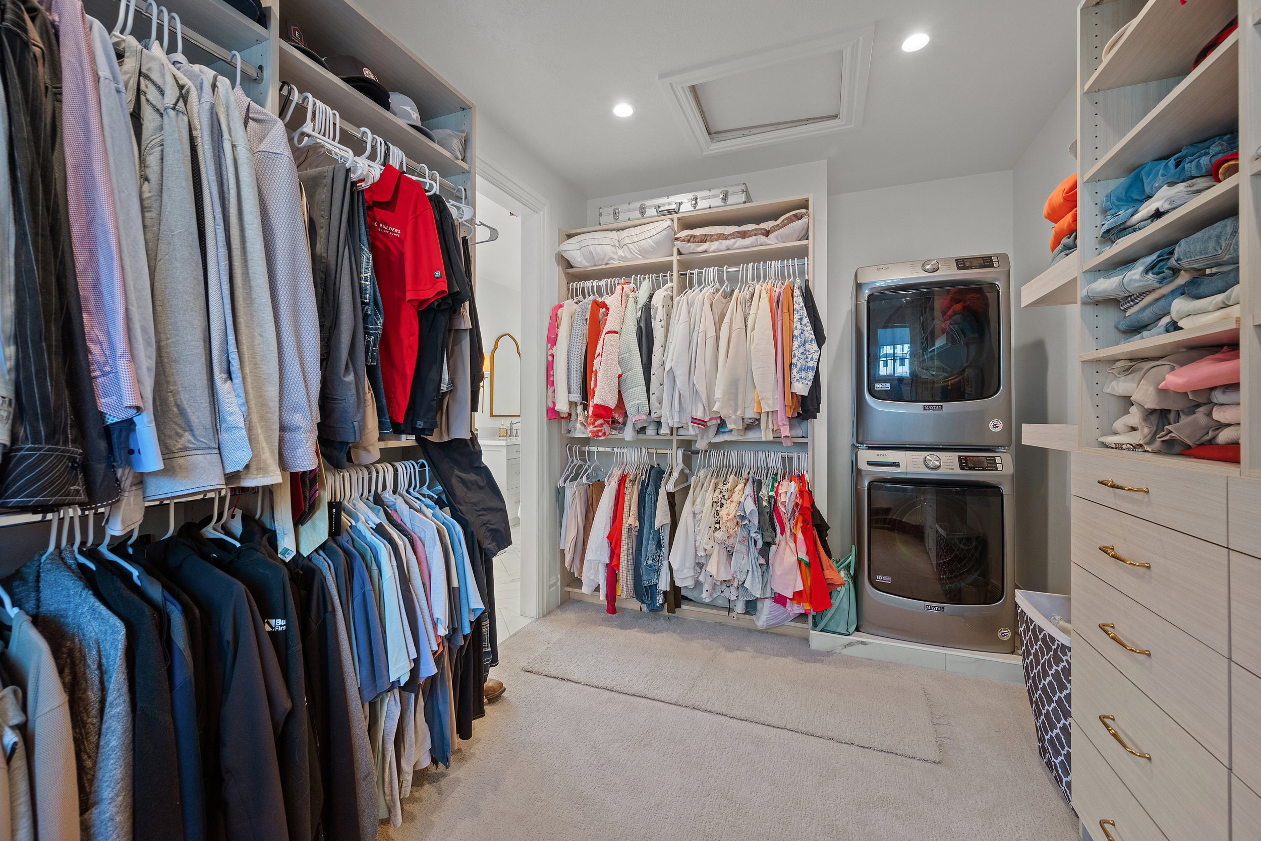 Built-in closet system featuring multiple hanging rods, shelving, and drawer storage