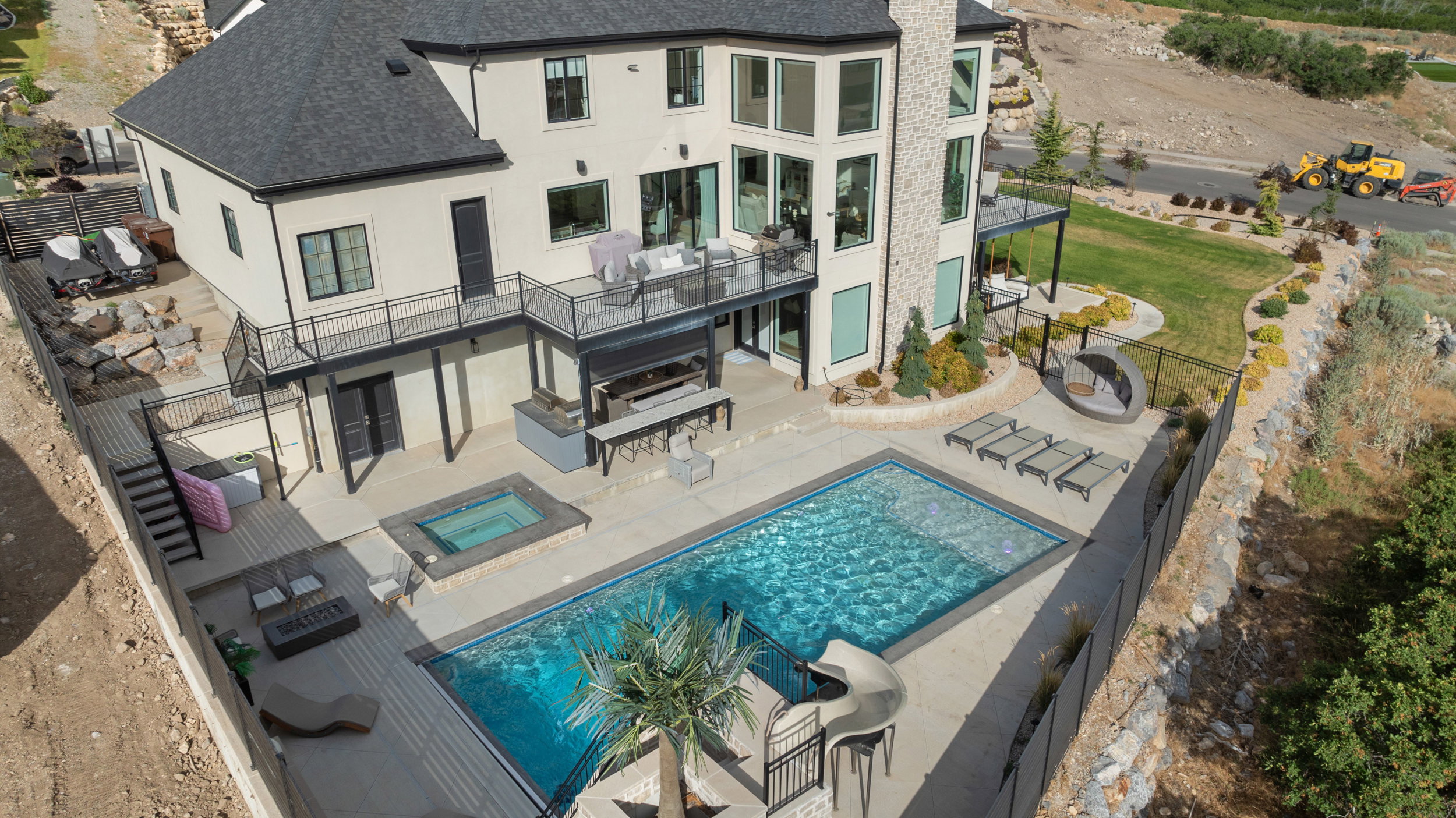 Expansive backyard oasis featuring a rectangular swimming pool, integrated spa, and an outdoor kitchen area