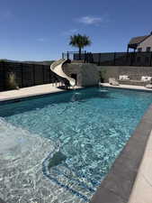 Rectangular swimming pool featuring integrated steps and a stone-clad water slide
