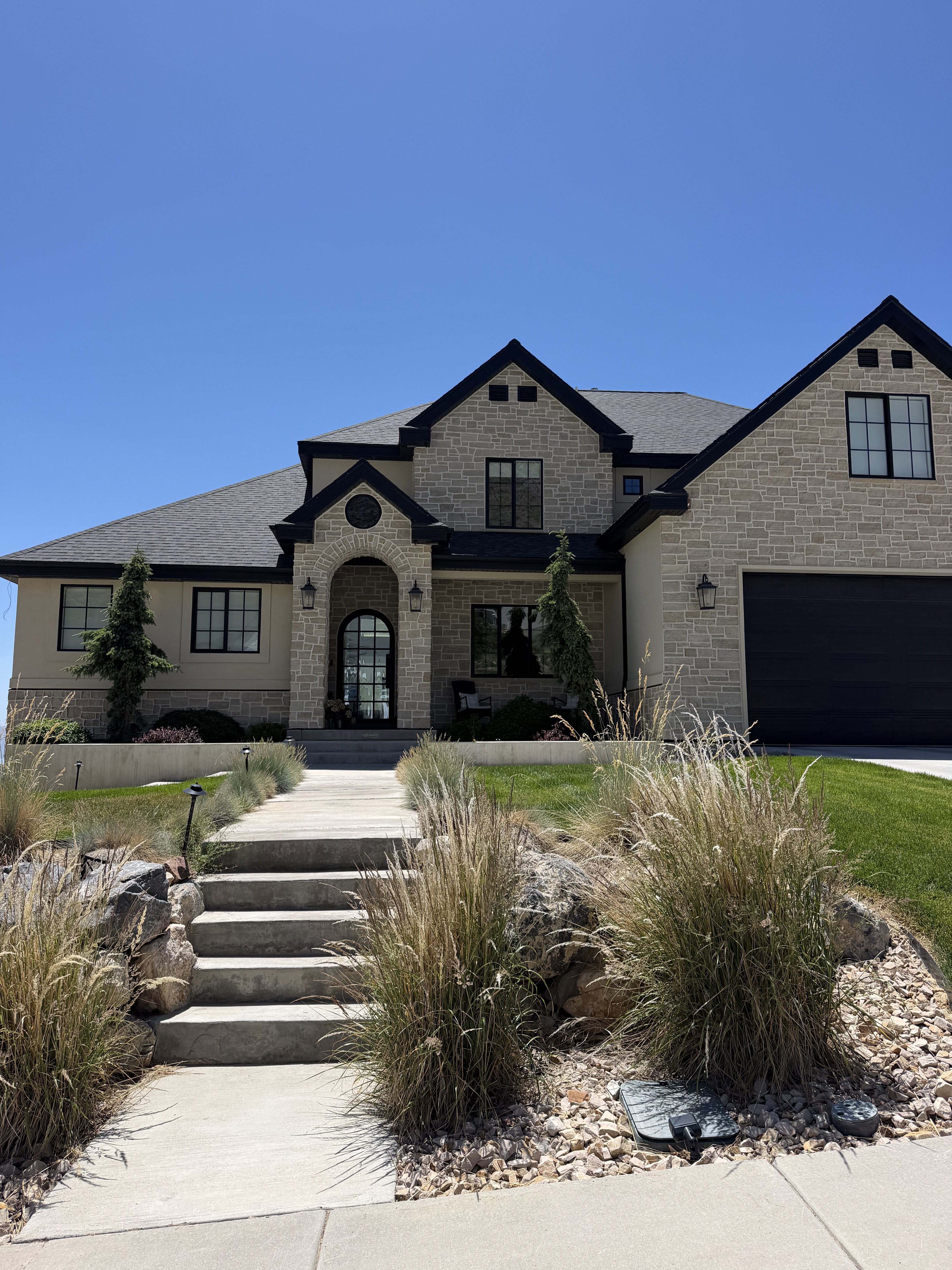 Stone facade residence featuring a prominent covered entry with arched details