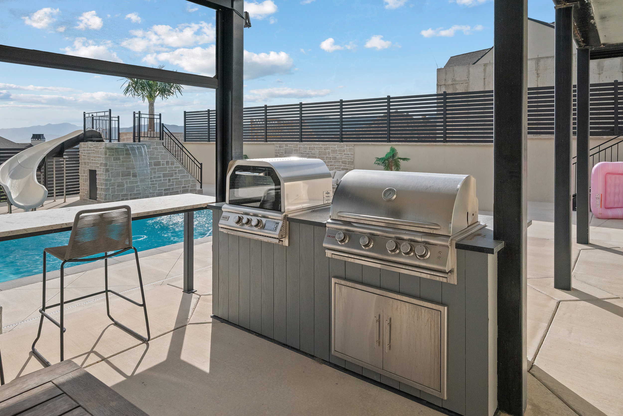 Outdoor kitchen featuring two stainless steel grills, integrated storage, and a stone-finish countertop