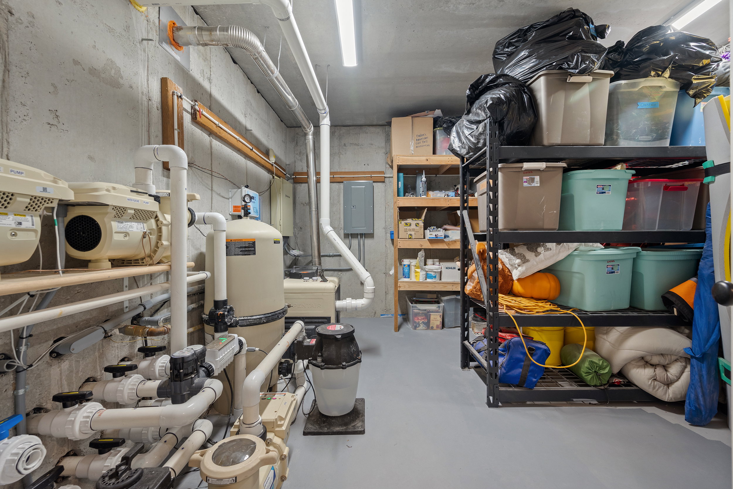 Dedicated utility room featuring pool equipment and extensive piping, concrete walls, concrete flooring, and overhead fluorescent lighting