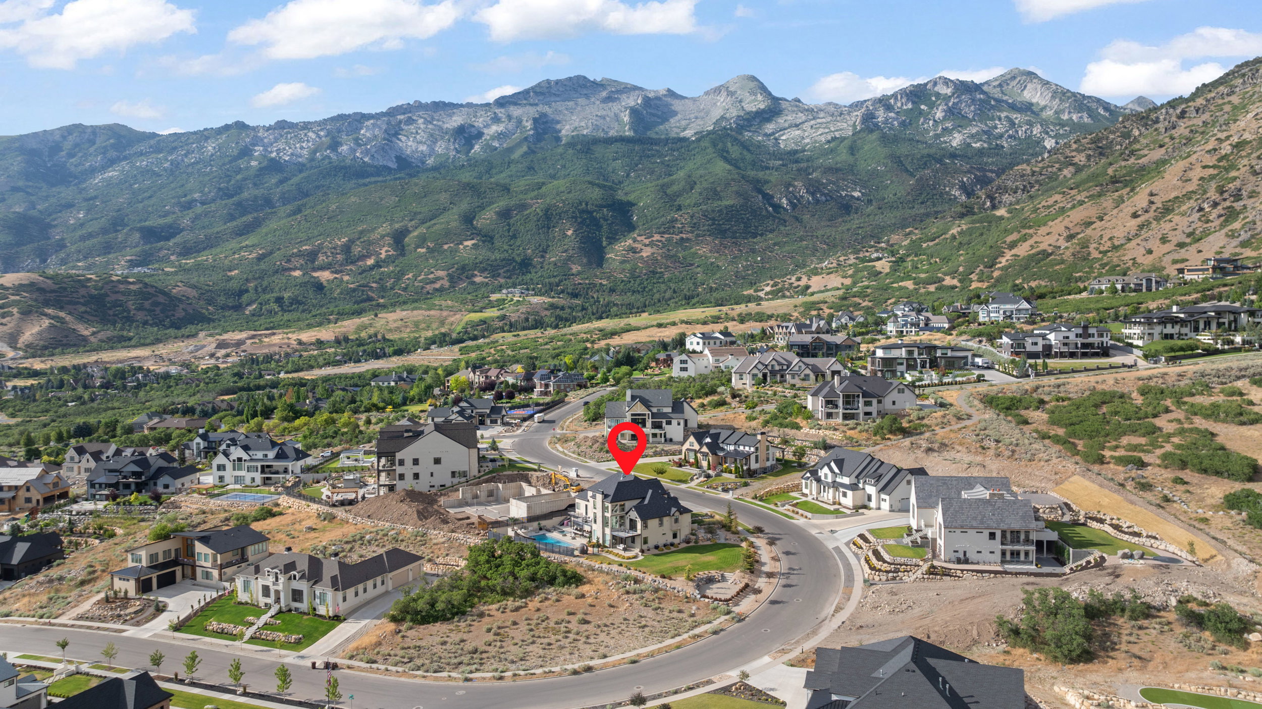 Elevated property featuring a multi-story residence with a dark roofline, surrounded by a residential area with a prominent mountainous backdrop