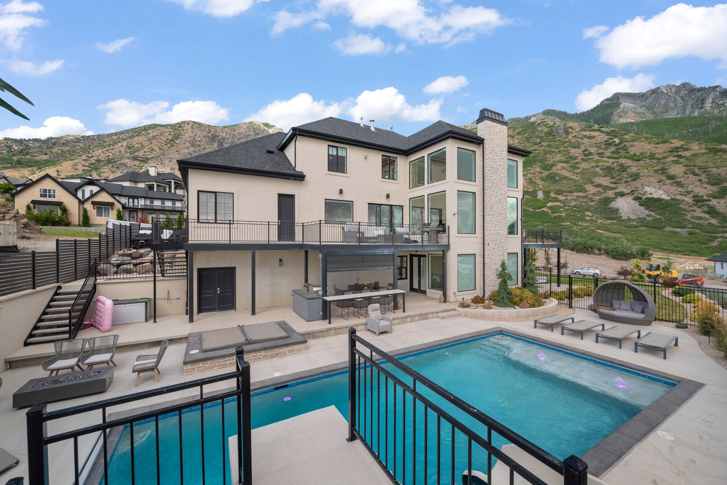 Rear exterior featuring a multi-level patio with an in-ground swimming pool, an integrated spa, and a covered outdoor kitchen area