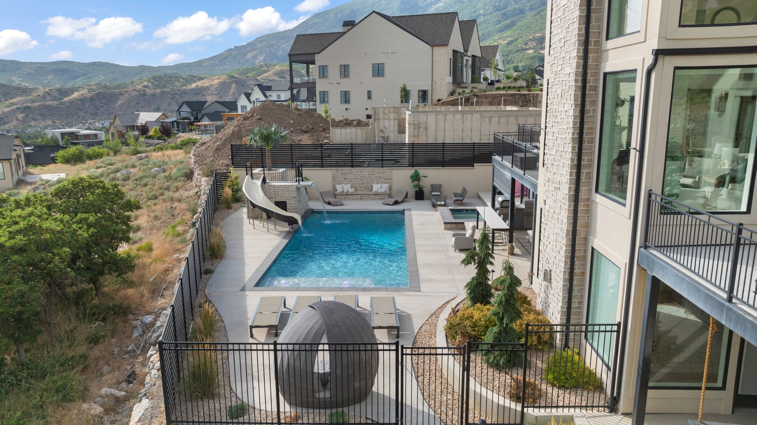 Expansive terraced backyard featuring a large swimming pool, integrated hot tub, and a water slide