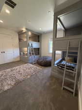Room featuring built-in bunk beds with integrated shelving and ladders, recessed lighting, carpet flooring, and a window with natural light