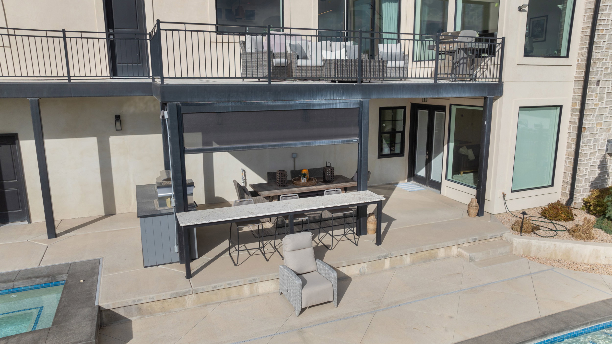 Expansive outdoor living area featuring a built-in barbecue station, covered patio, outdoor bar, and integrated spa