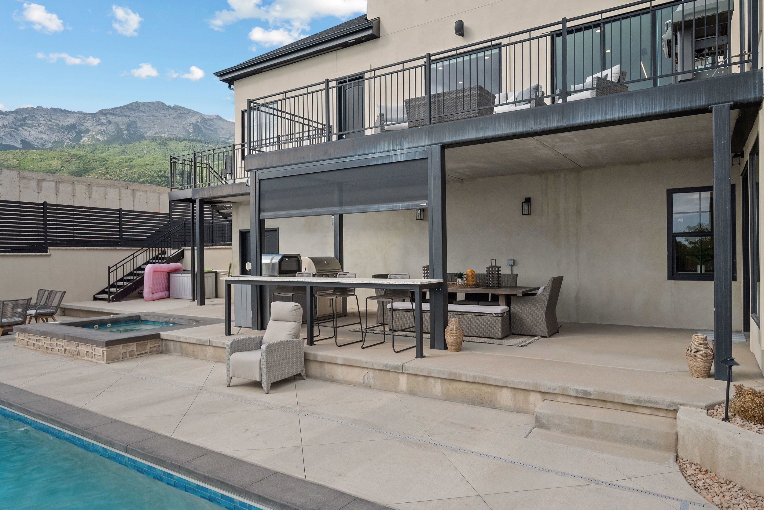 Expansive outdoor living area featuring a built-in pool, integrated hot tub with stone surround, and an outdoor kitchen with an extended countertop